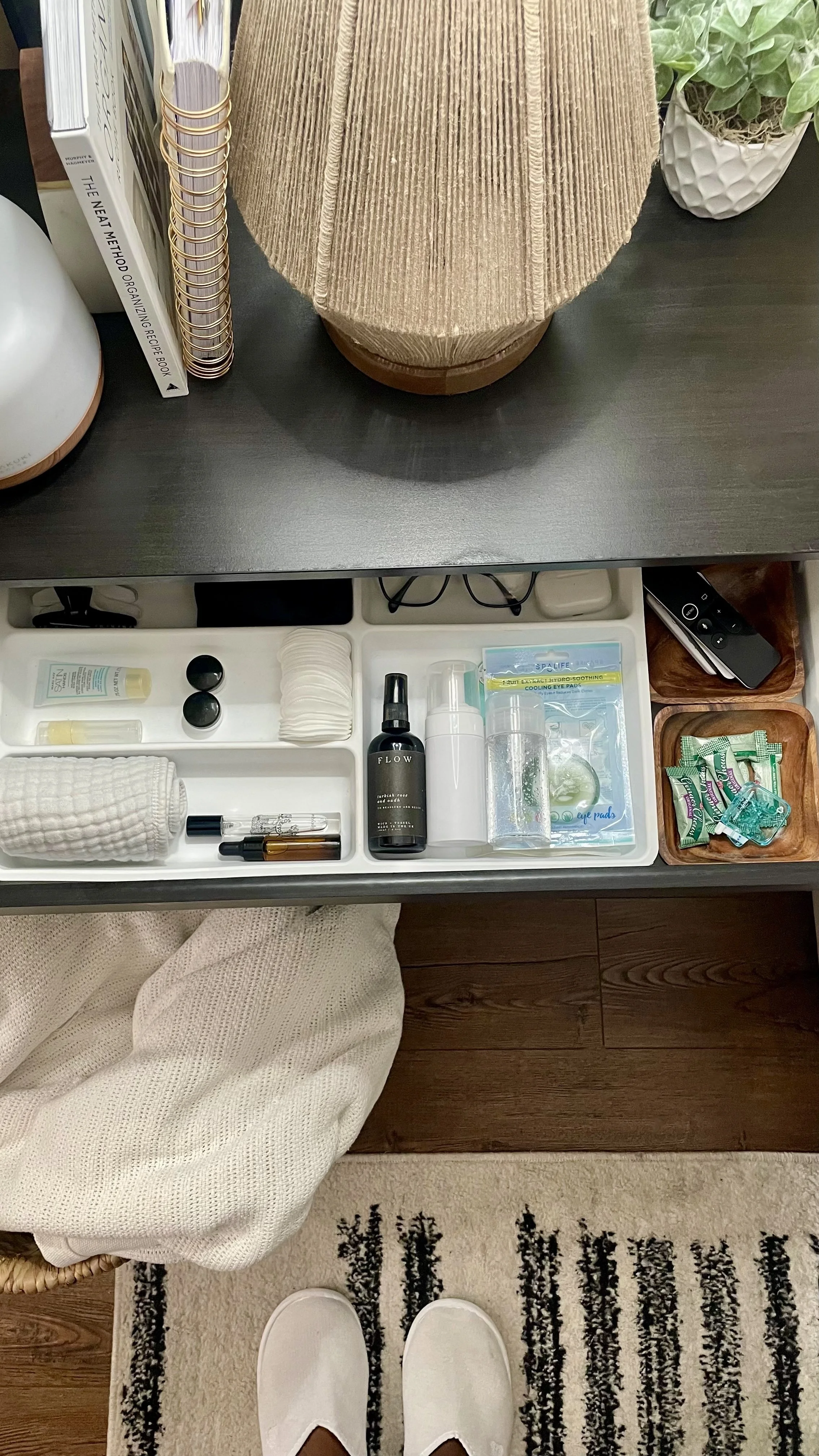 Nightstand drawer neatly organized with skincare, fragrance, glasses, and self-care essentials