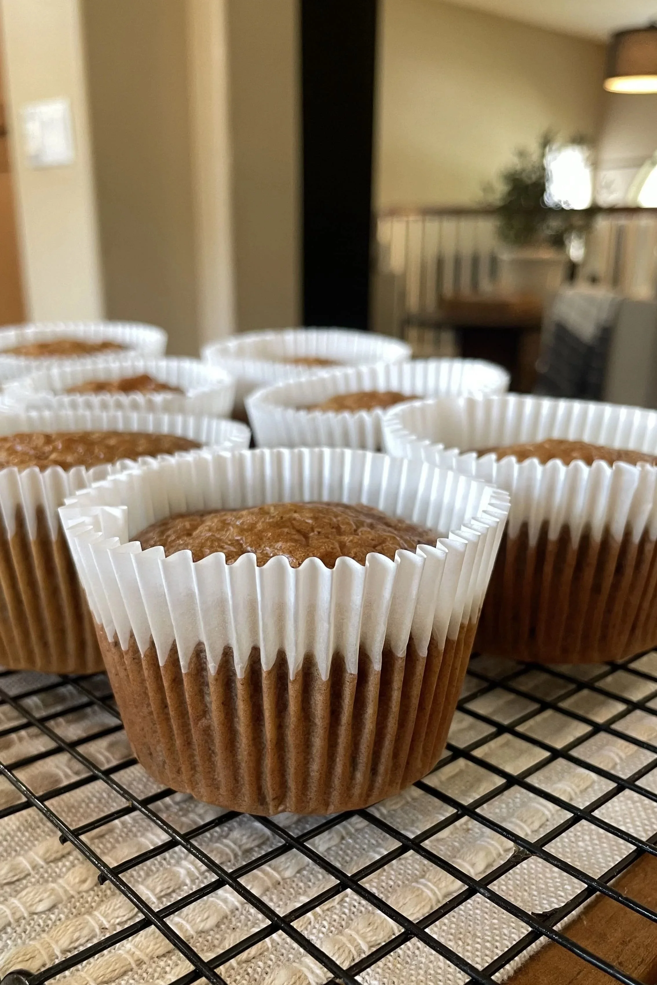 Freshly baked carrot cake muffins cooling on a wire rack in white parchment liners.