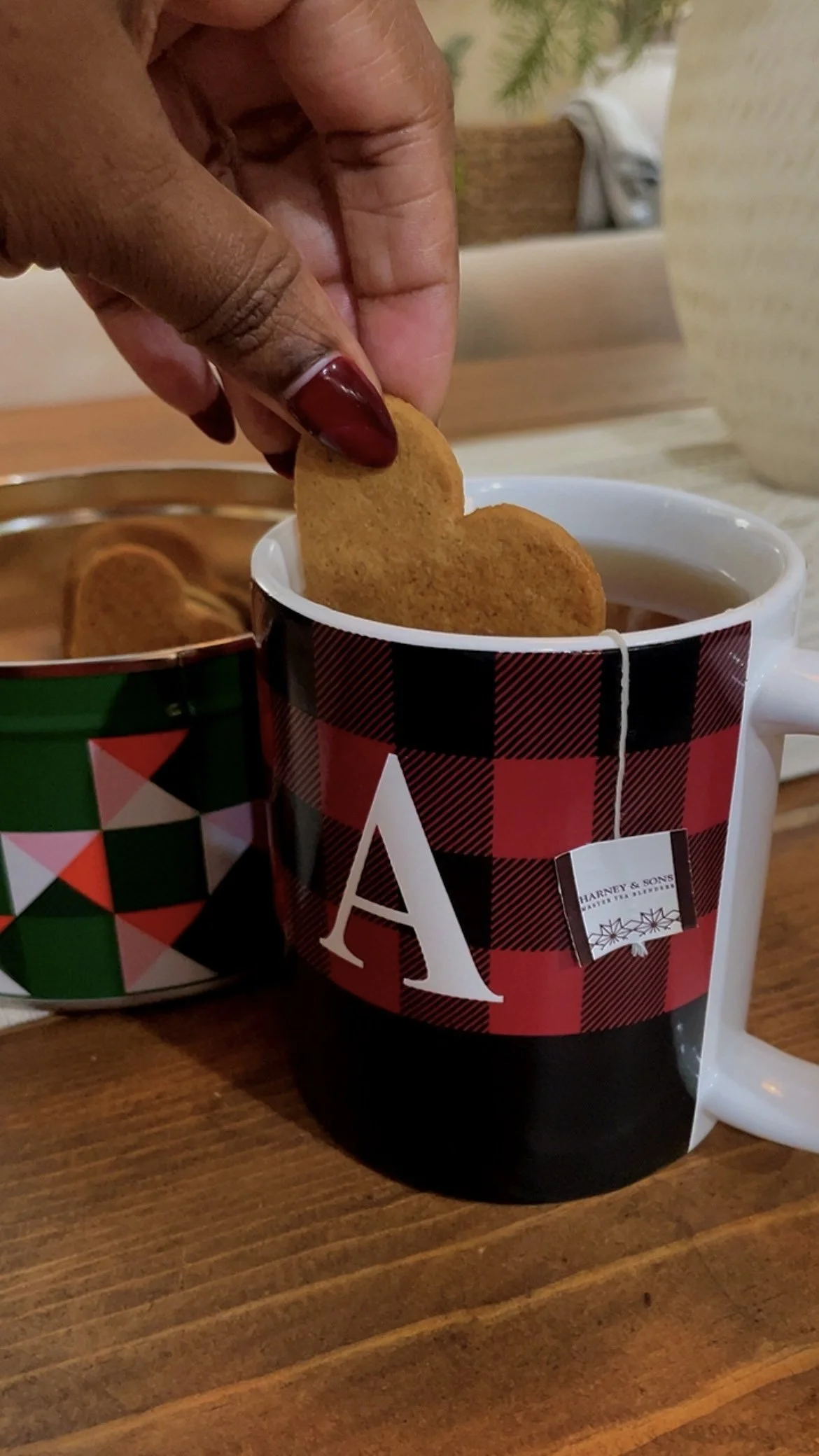 Hand dipping a homemade cookie into a warm mug of tea, embracing a slower and softer December day