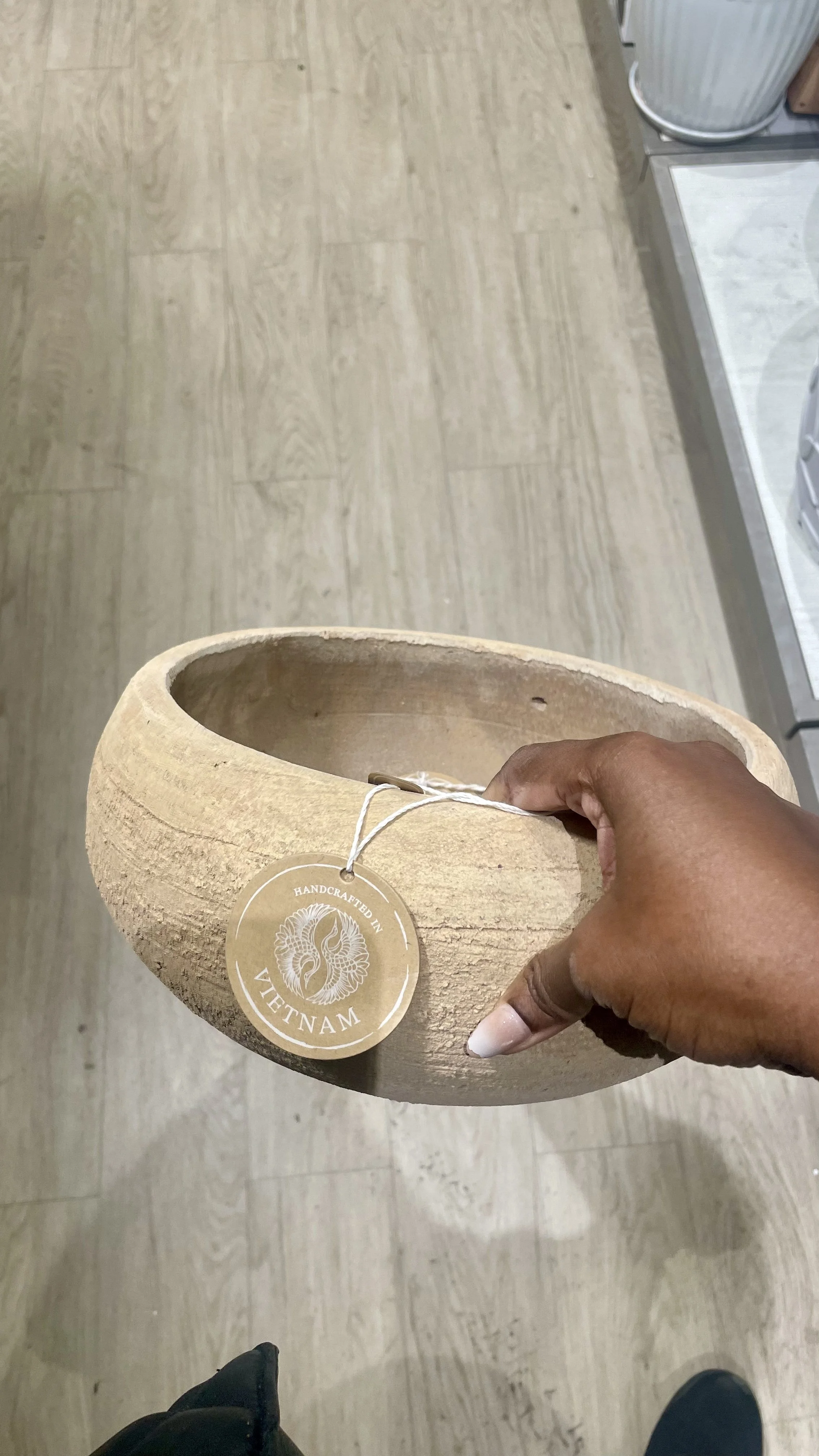 Hand holding a rustic, shallow clay planter with a natural textured finish, found at HomeGoods for an indoor herb garden