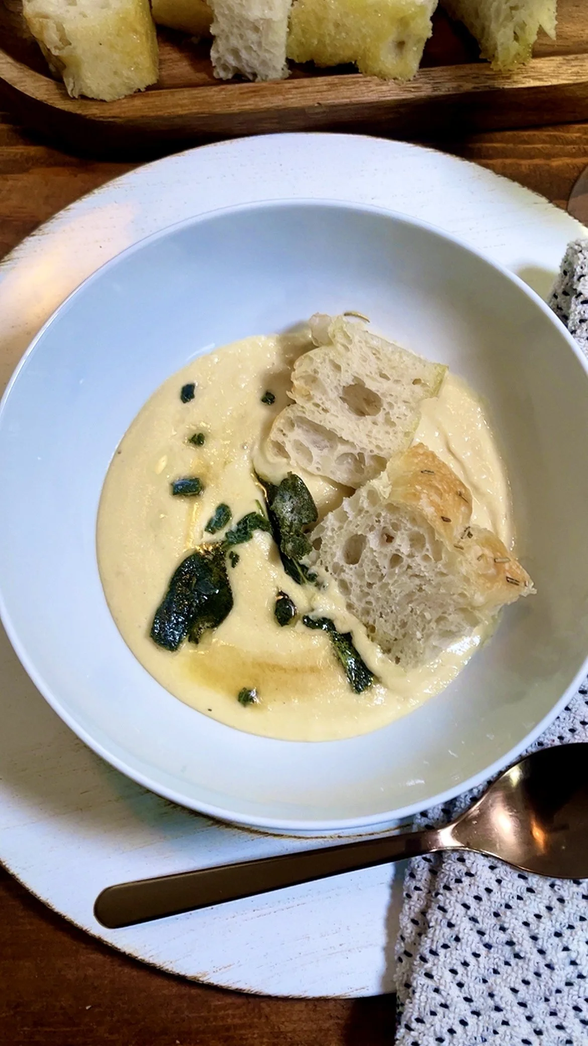 soup in a bowl with focaccia bread a spoon cloth napkin and truffle