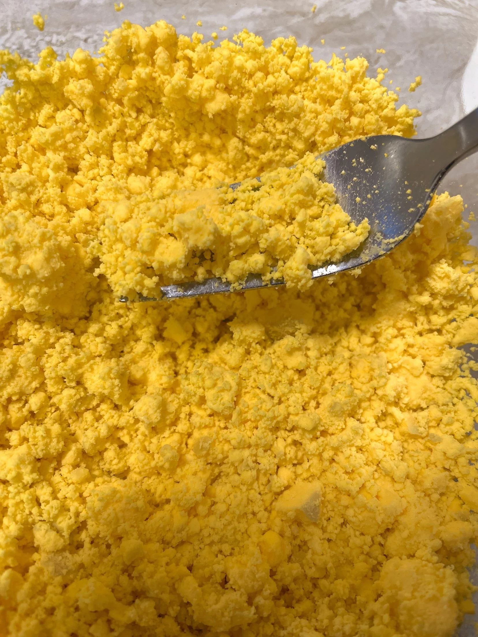 Mashed hard-boiled egg yolks in a glass bowl for deviled egg filling