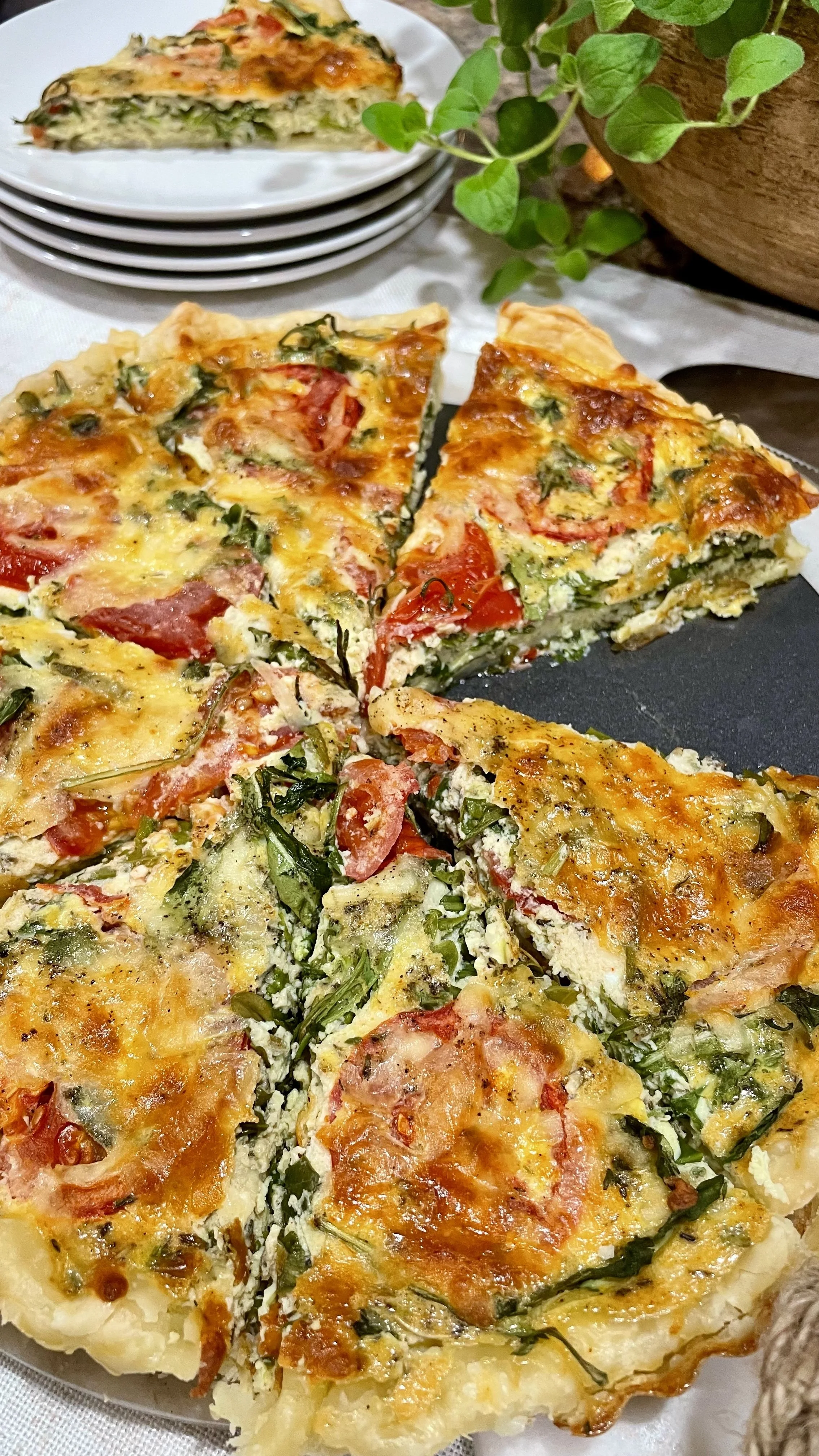 Sliced herb quiche served on a plate with fresh greens and a cozy kitchen table setting