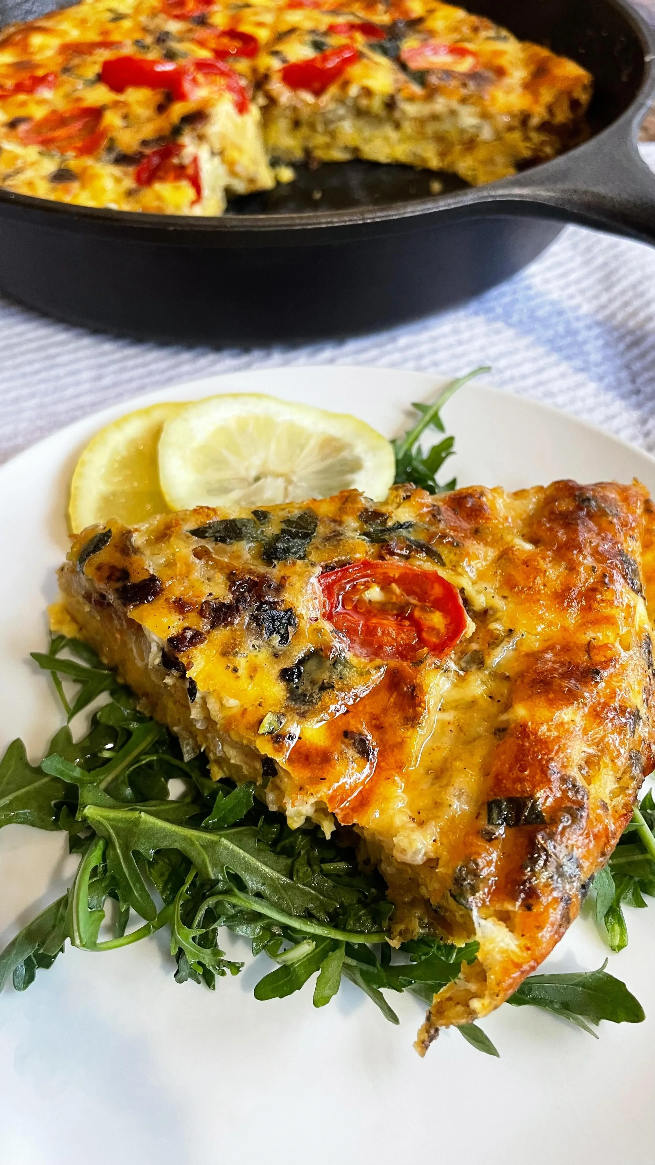 Homemade tater tot frittata with bacon, melted cheese, cherry tomatoes, and fresh herbs baked until golden brown.