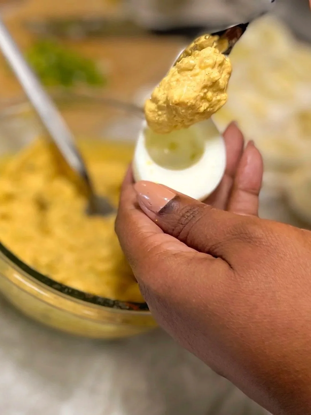 Filling a deviled egg with creamy yolk mixture using a spoon