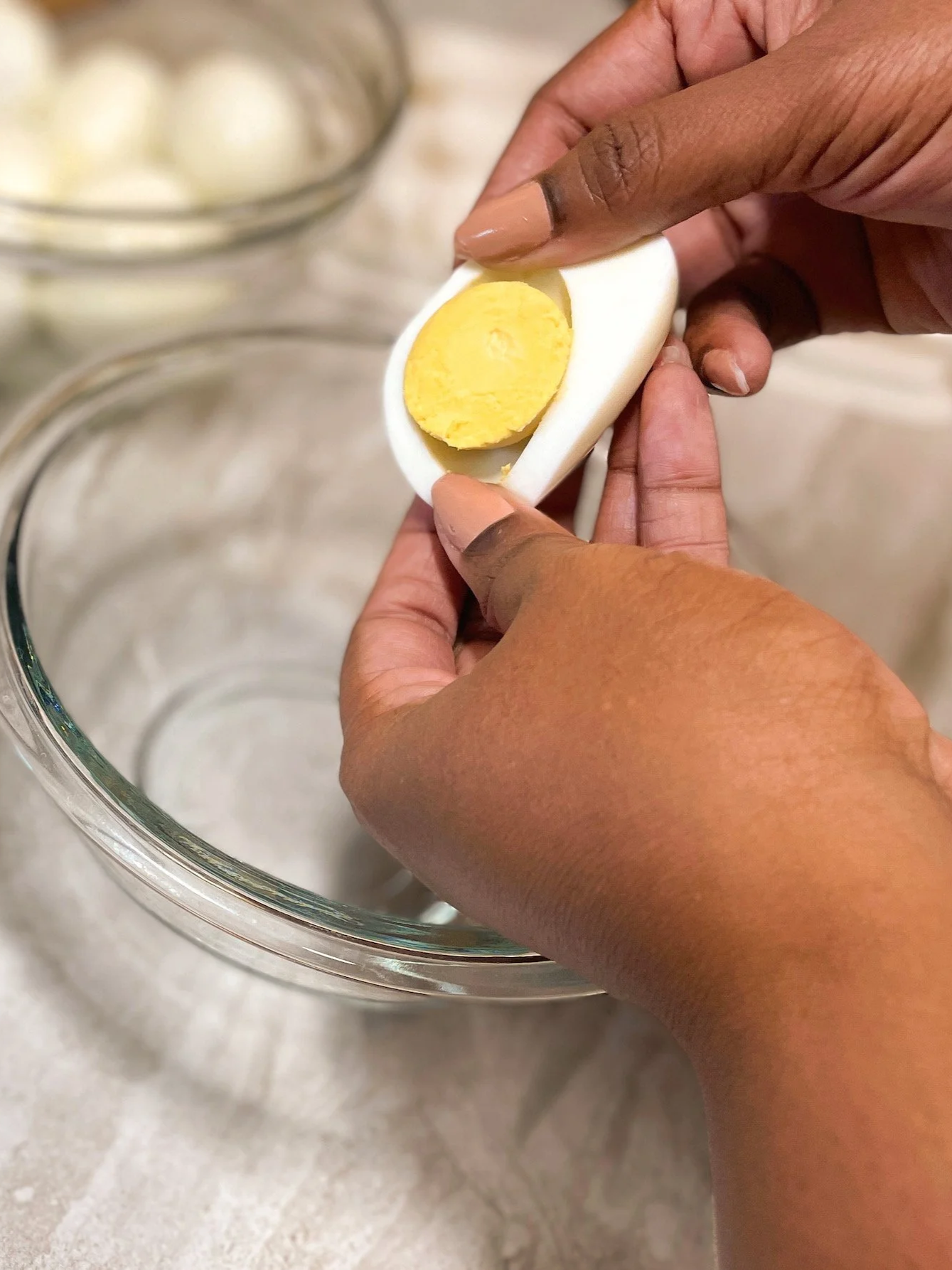 Removing the yolk from a hard-boiled egg white by gently pressing it out by hand
