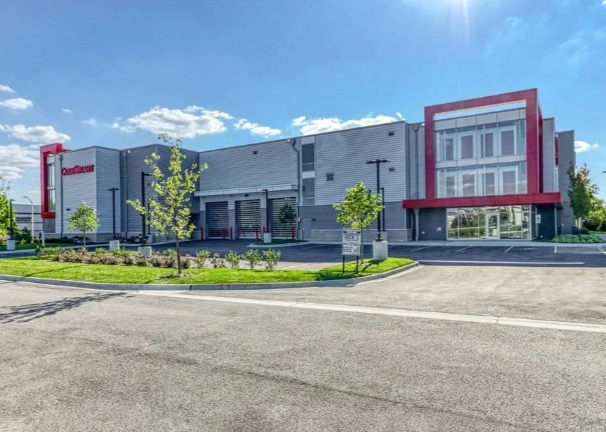 Exterior of a large retail store with a parking lot and some small trees in front, clear blue sky overhead.