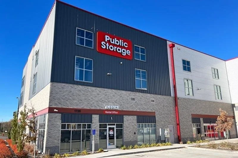 Exterior of a Public Storage building with a rental office entrance, gray brick facade, and red and white accents.