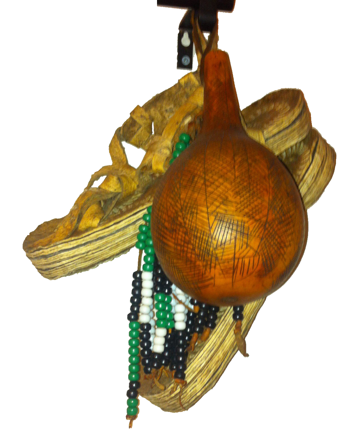Decorative hanging ornament with a large amber-colored gourd-shaped piece (tulle), beads in green, white, and black, and a traditional women's shoes.
