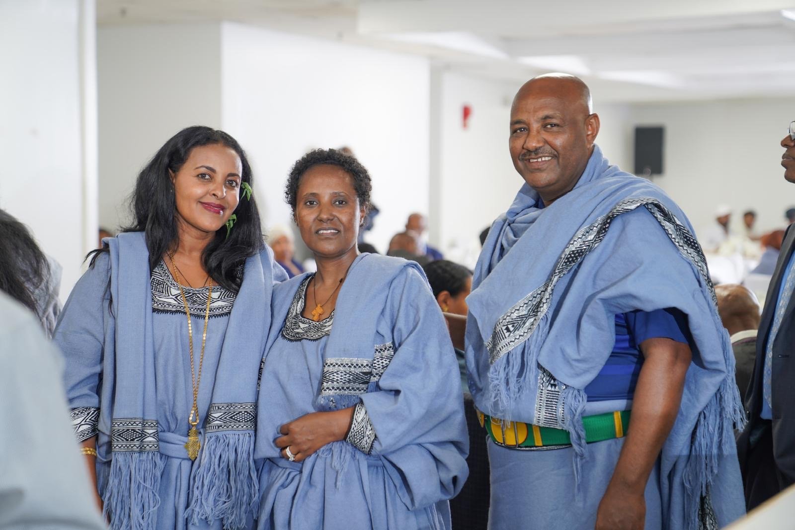 Group of four people, three women and one man, wearing traditional Ethiopian clothing in an indoor setting at an event or gathering.