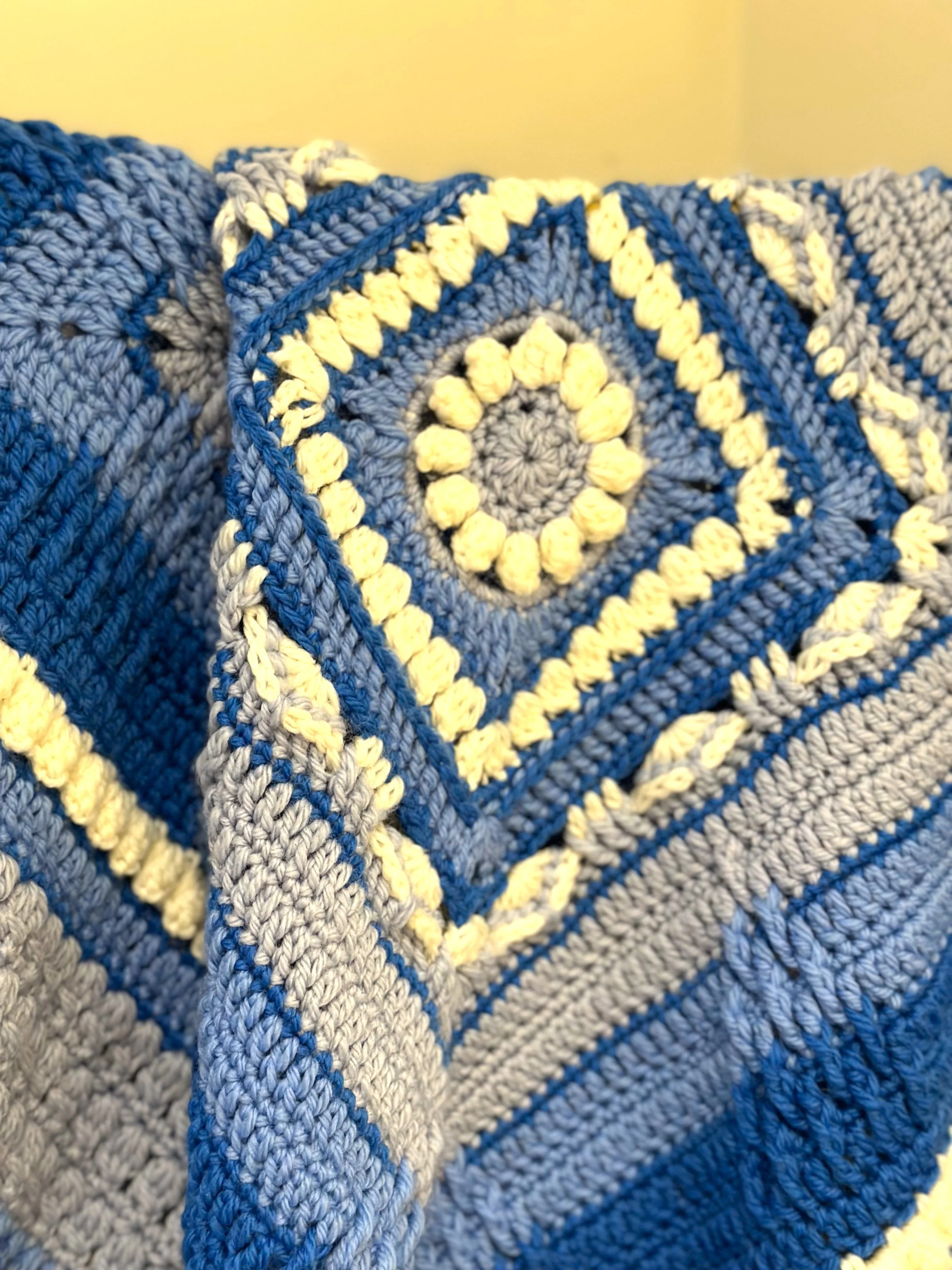 Blue, white, and gray crochet blanket with geometric patterns and intricate design.