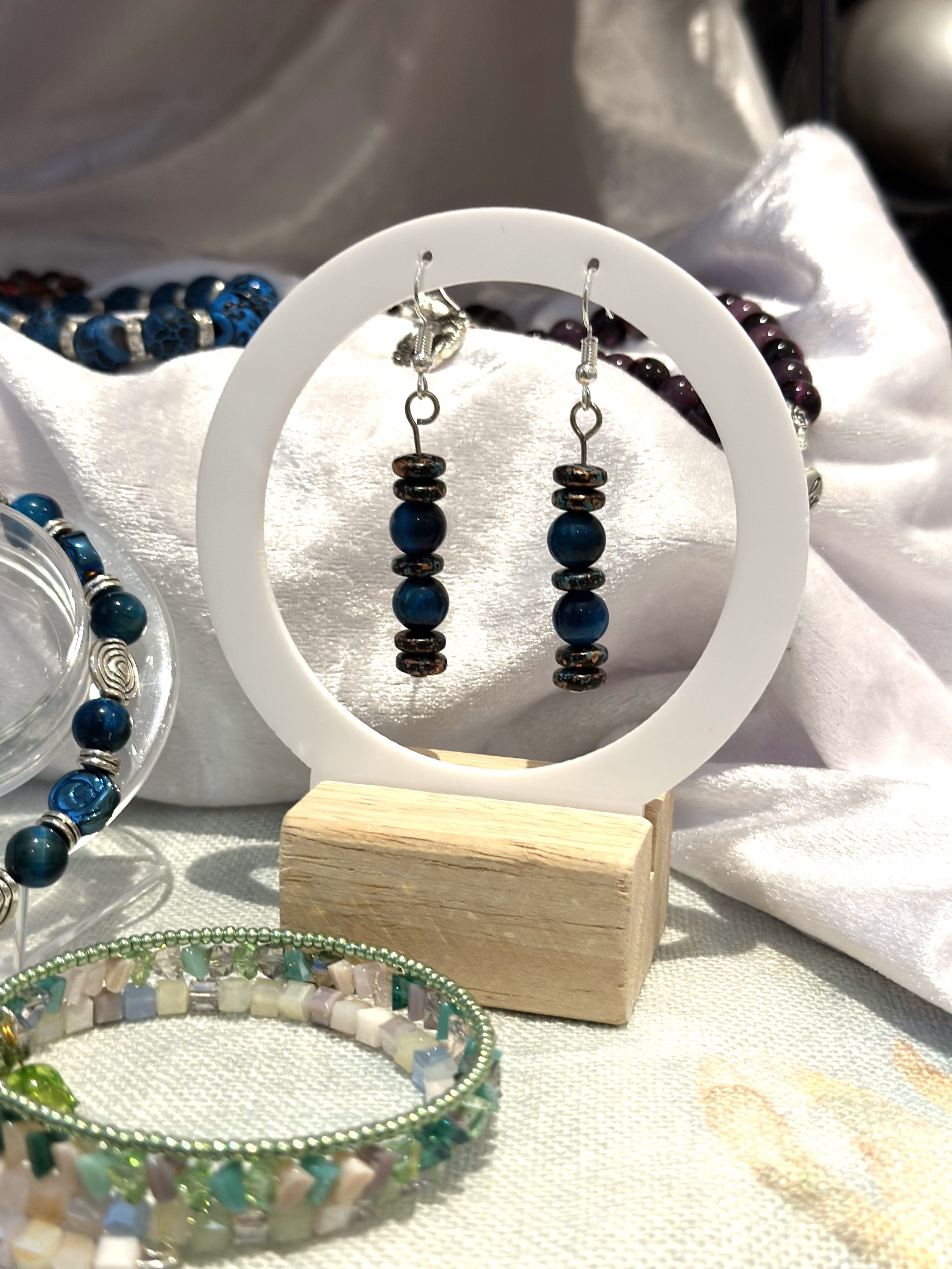 Blue beaded earrings on display with assorted bracelets