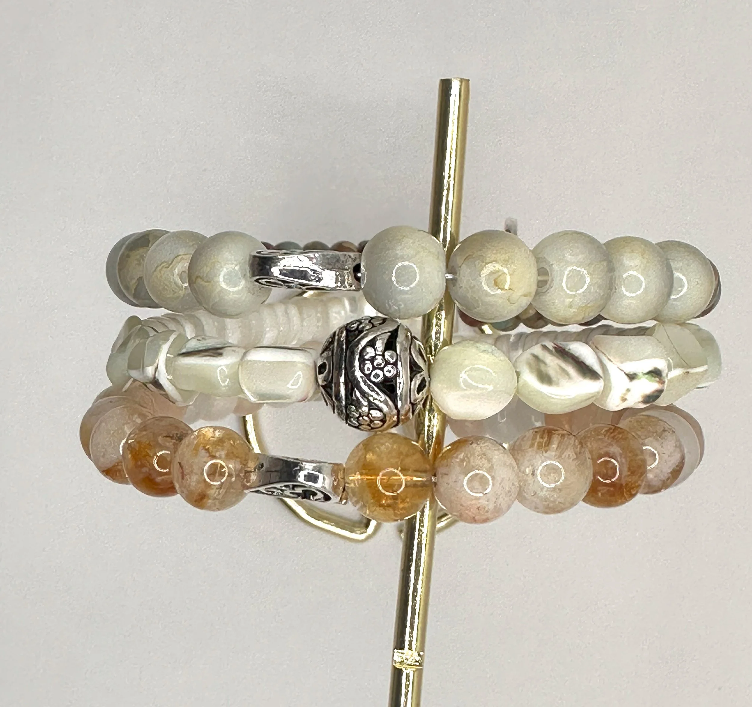 Stack of beaded bracelets with metal accents on a display stand.
