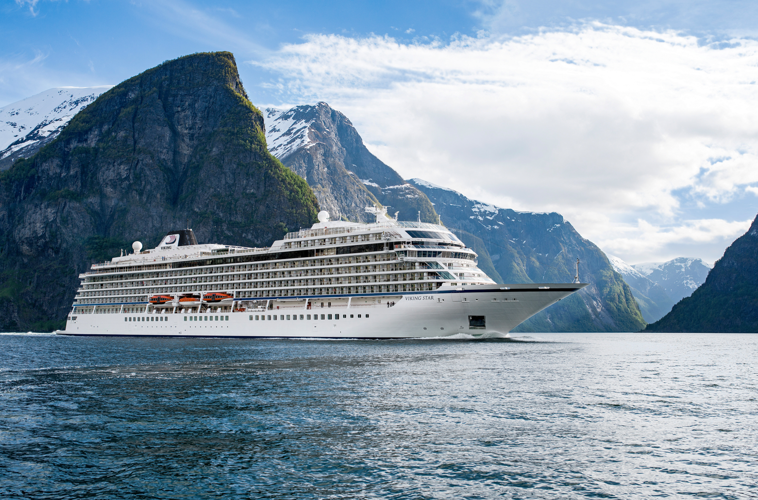 Large cruise ship docked near a beach with turquoise water and white sand.