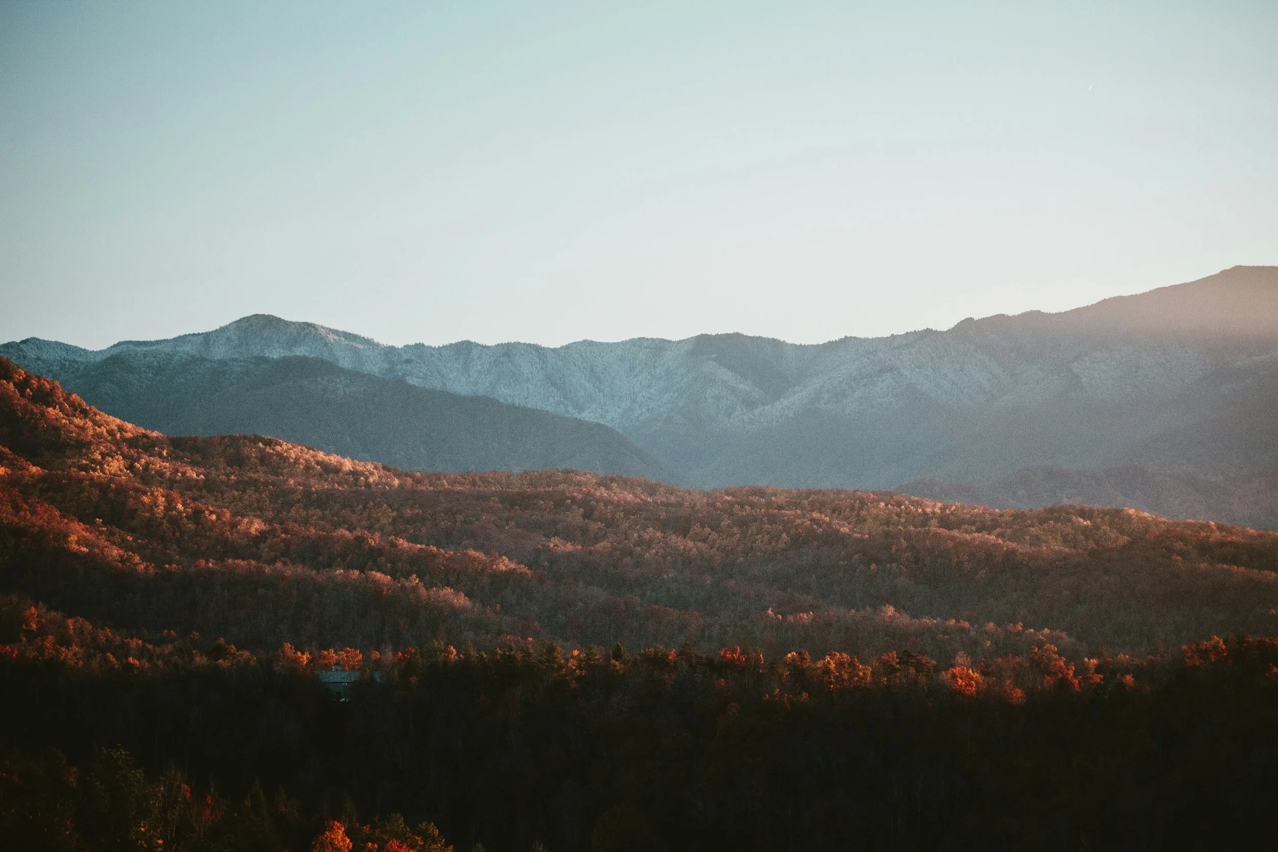 Scenic view of mountain range with forested hills and a clear sky.