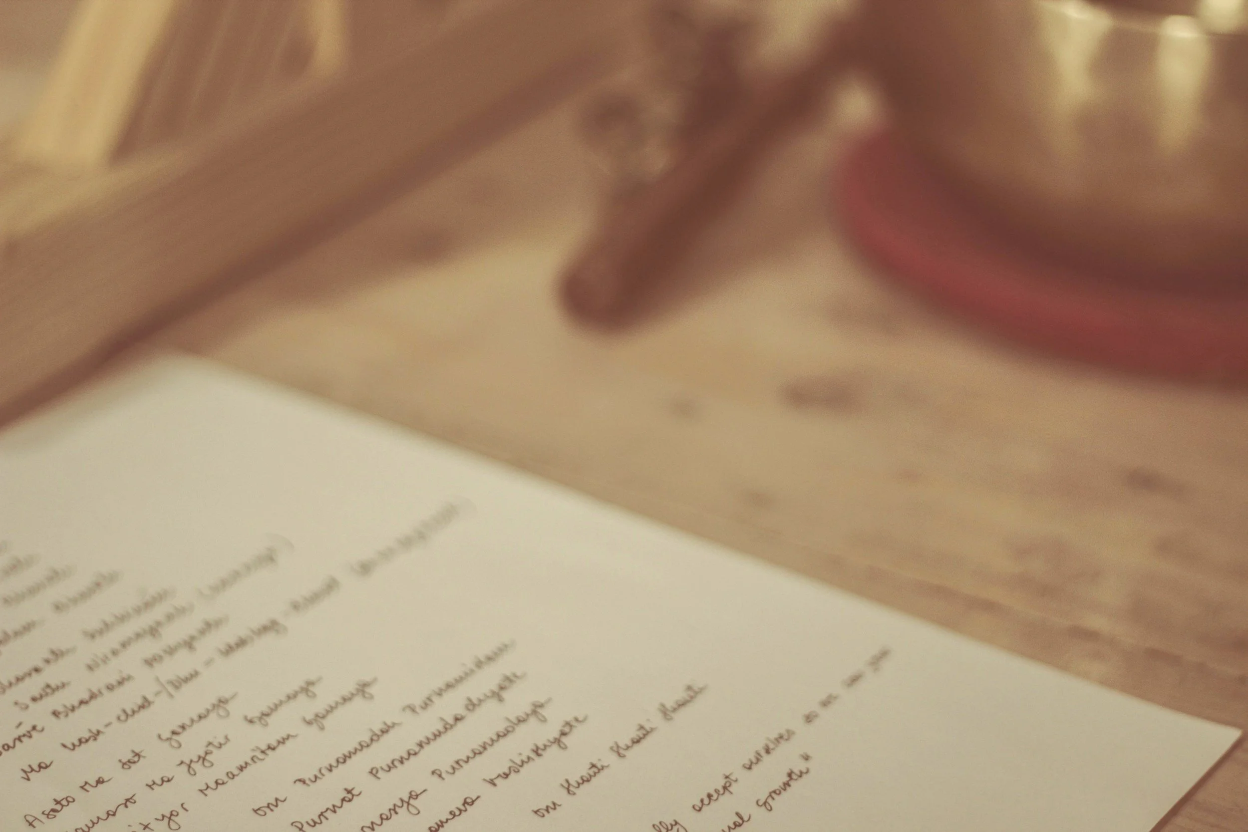Close-up photo of a page in a book with cursive writing, partially in focus, with a blurred background.