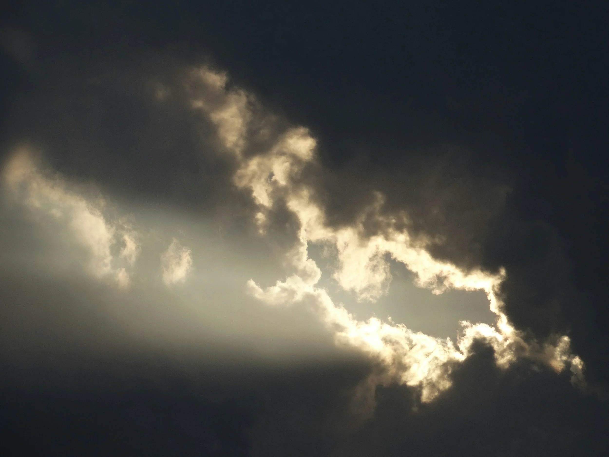 Dark stormy clouds in the sky with some sunlight breaking through.