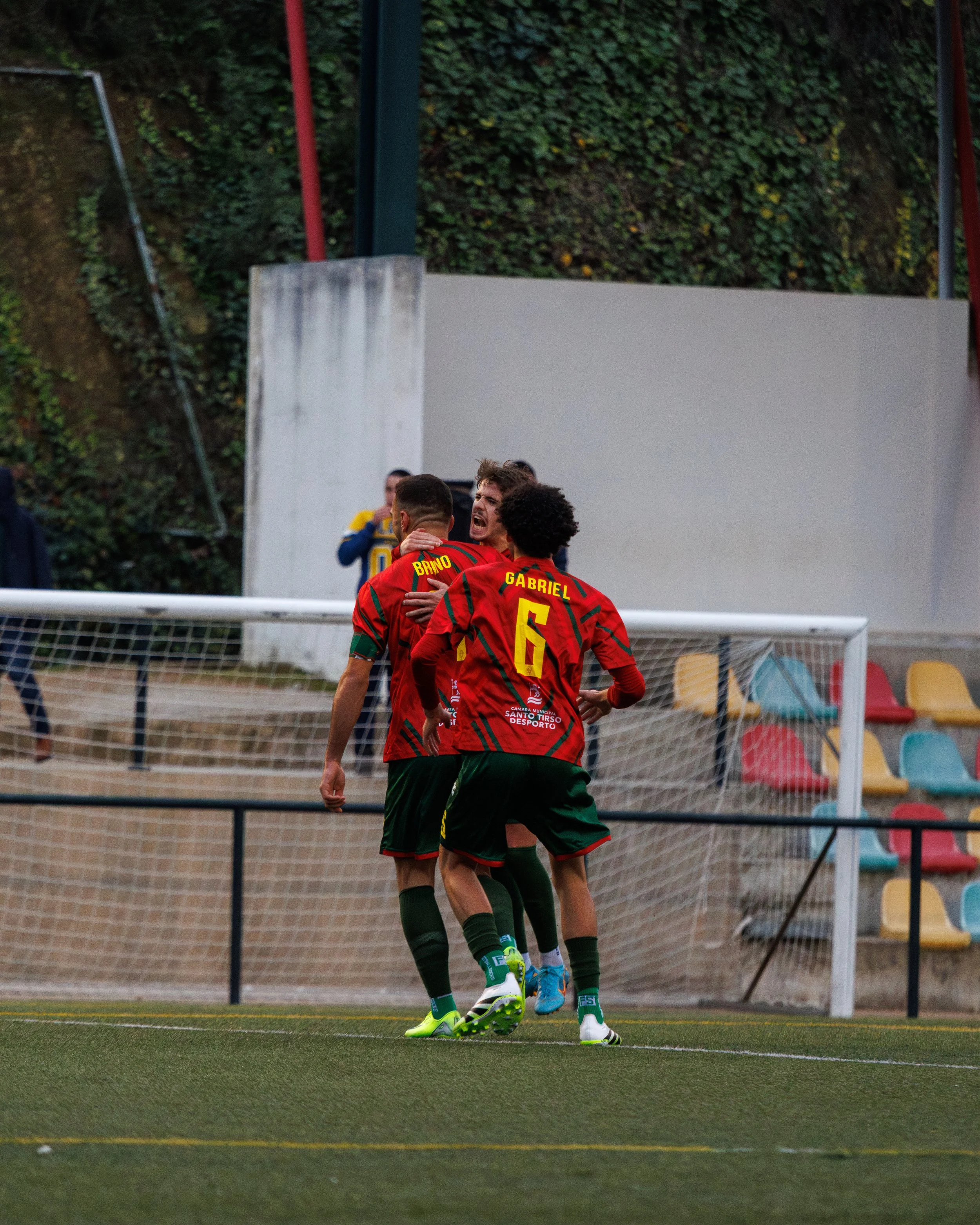 Soccer players in red and green jerseys celebrating on the field, with one player having the number 6 on their back.