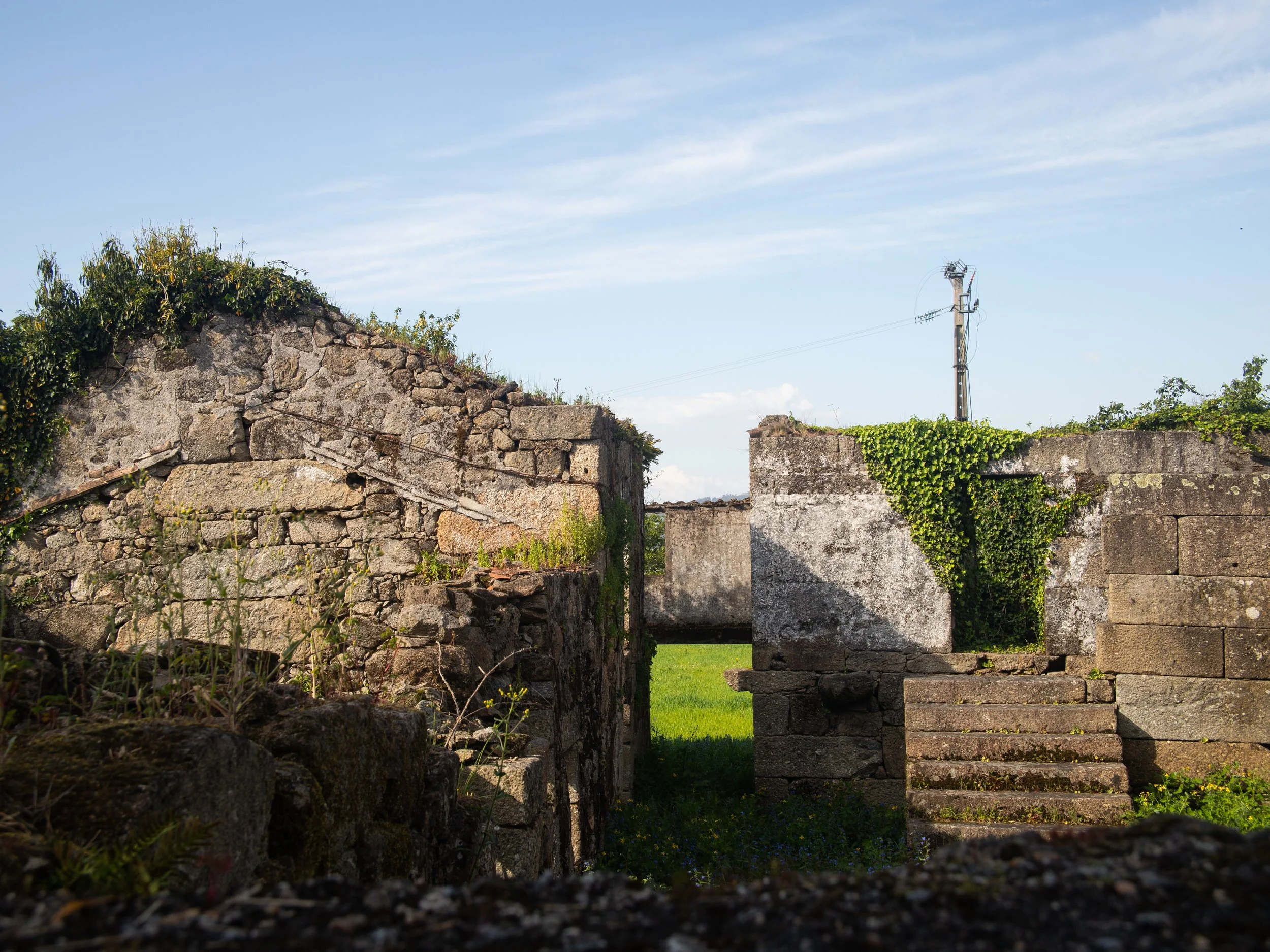 Old stone ruins with steps and greenery under a blue sky.