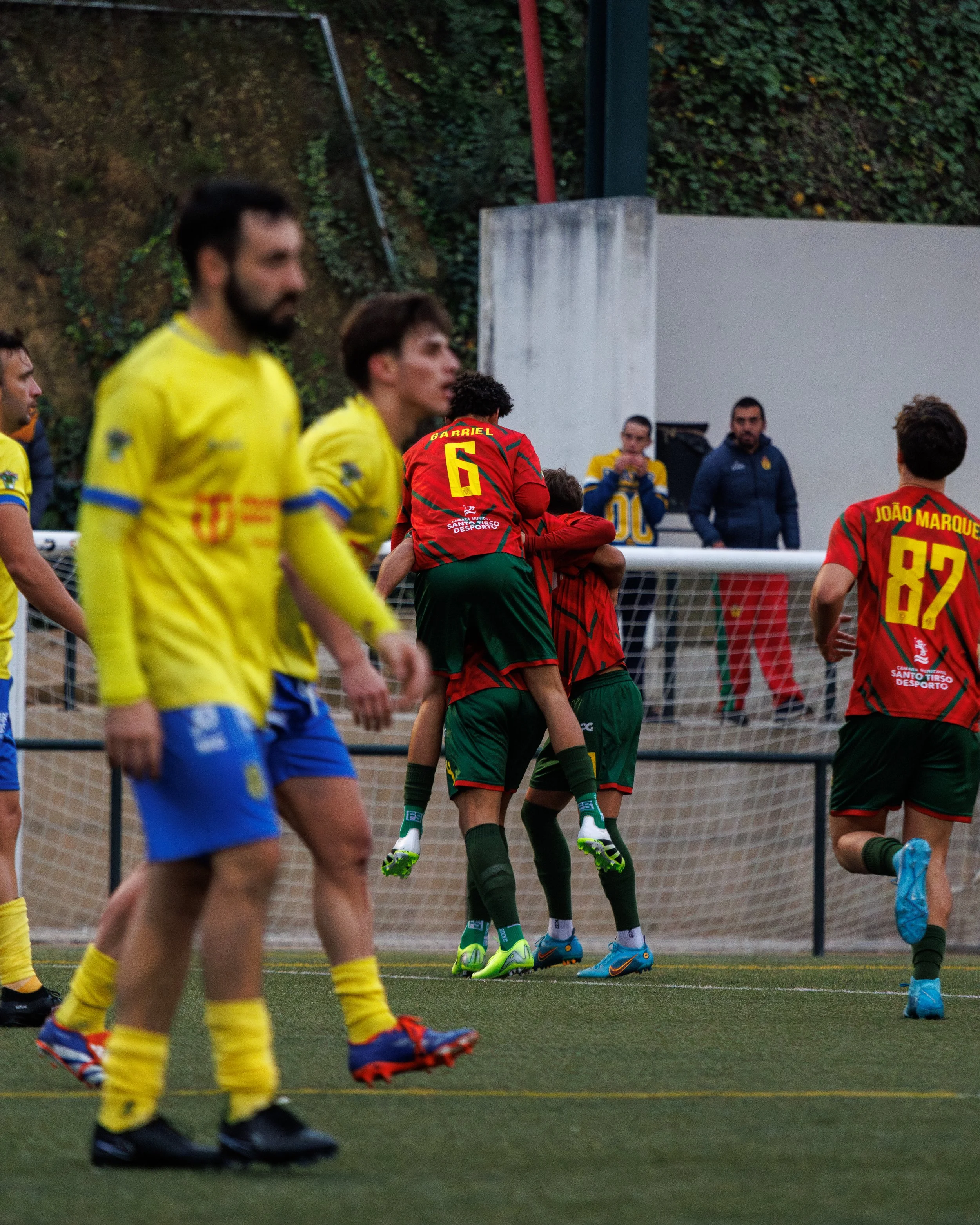 Soccer players in yellow and red uniforms celebrating and walking on the field.