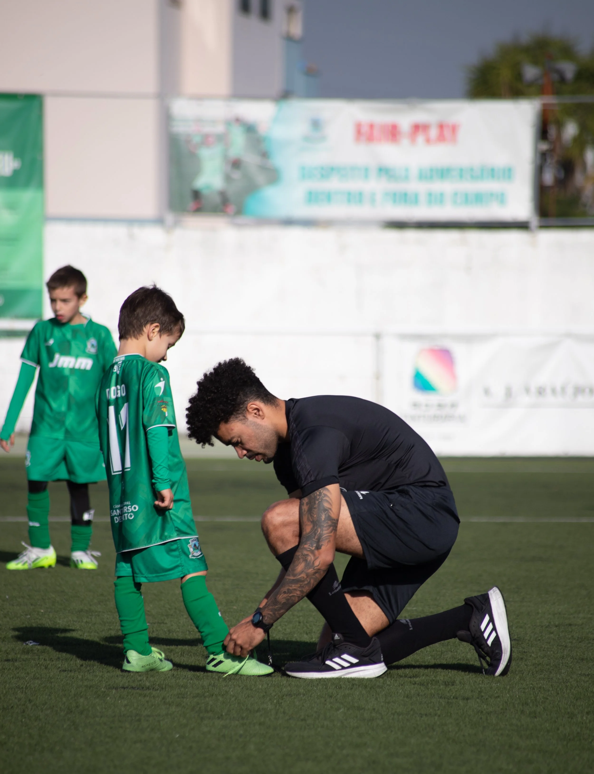 Football referee tie young kid's shoe, fair-play