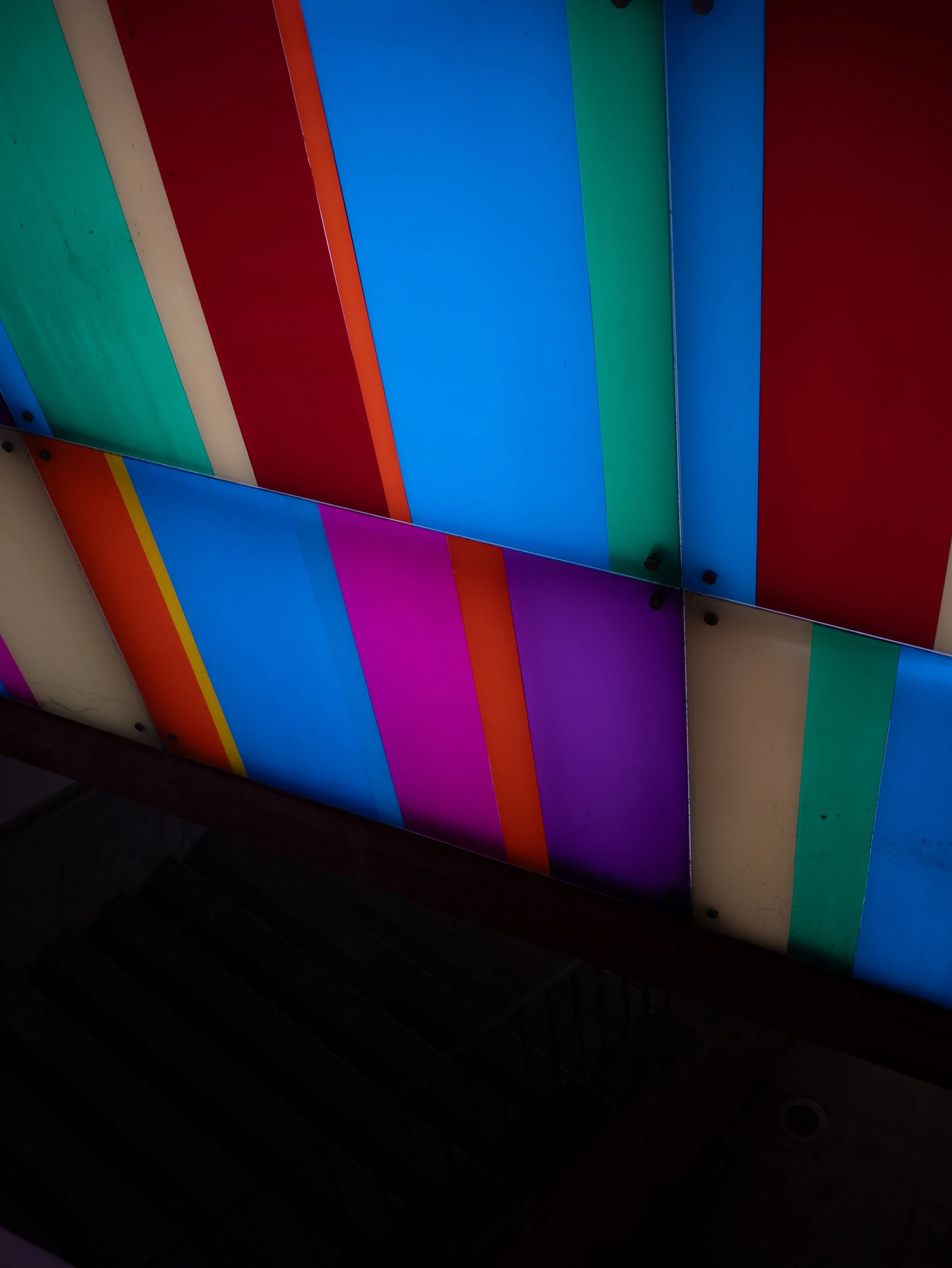 Colorful illuminated panels with vertical stripes in blue, purple, green, red, orange, yellow, and beige.