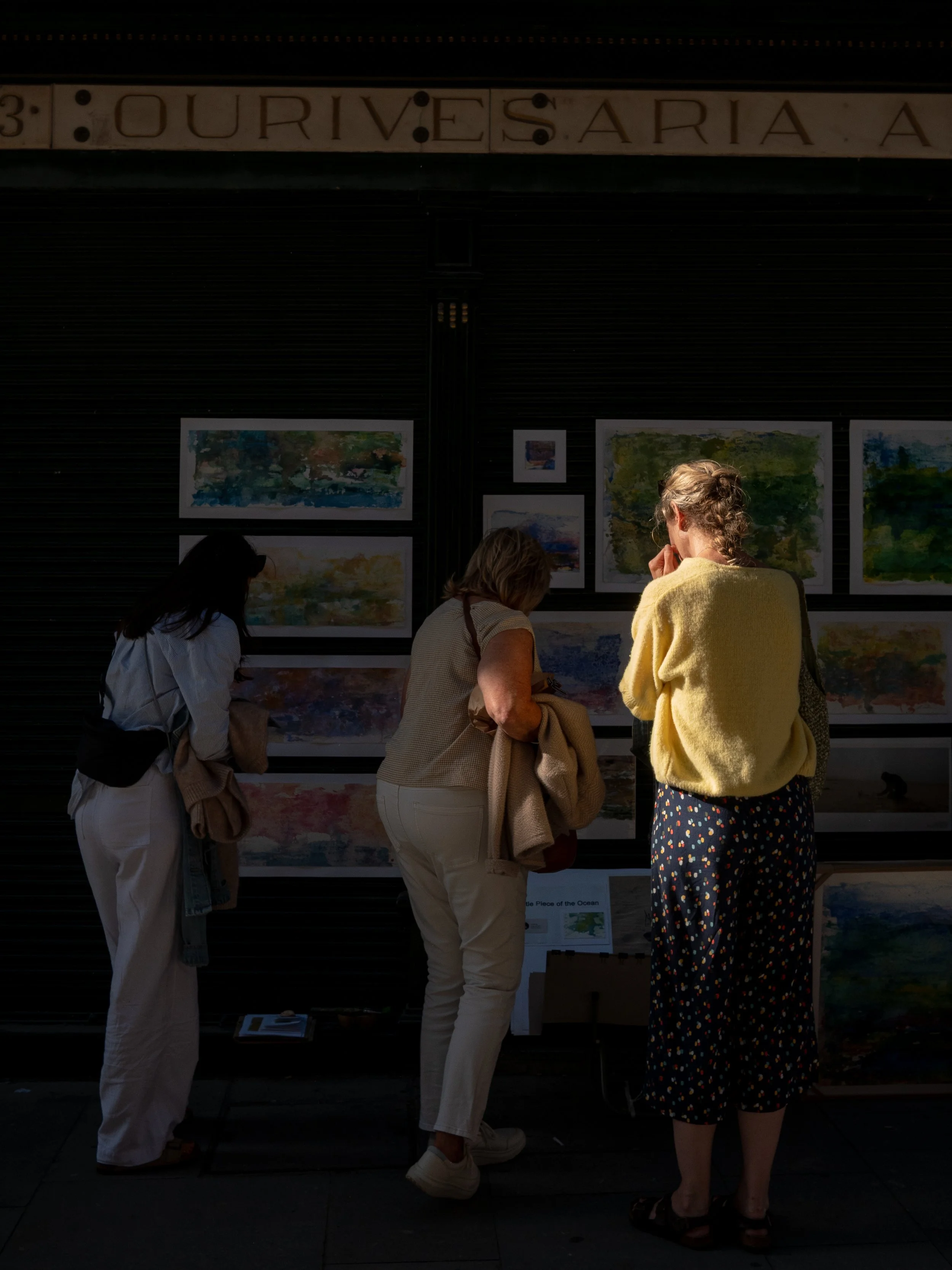 Three woman looking at paintings