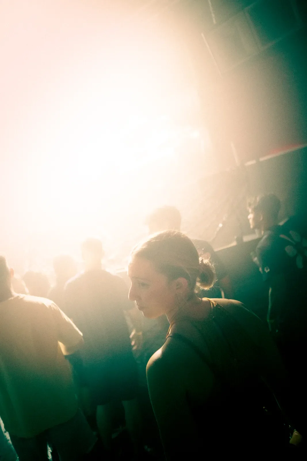 Una mujer en una pista de baile con luces brillantes y una multitud de personas en el fondo.