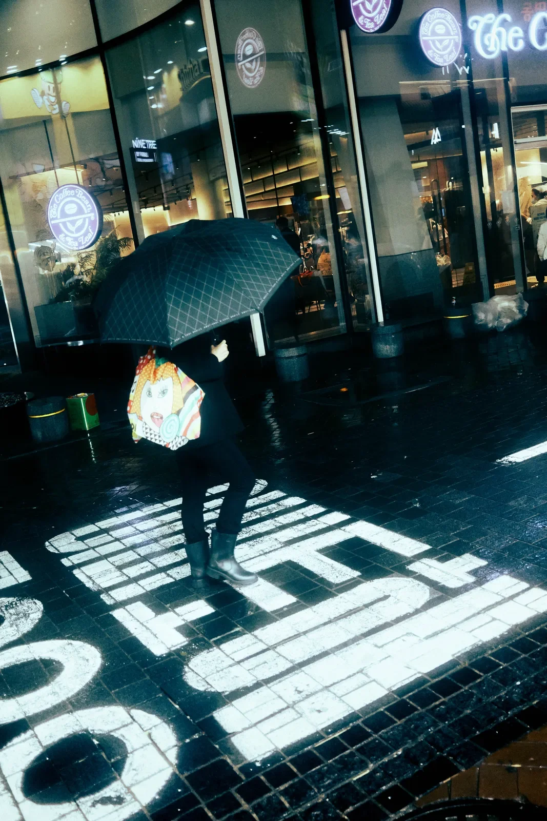 Persona con paraguas caminando en la calle frente a un establecimiento de Starbucks en un día lluvioso.