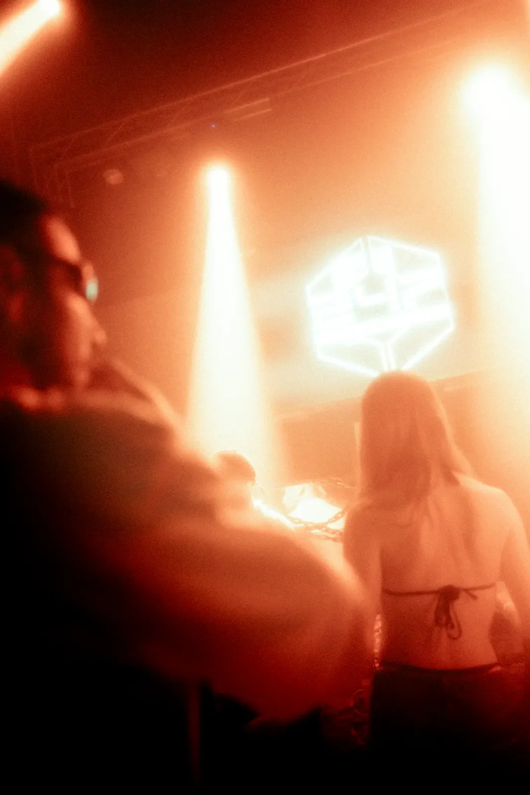 Personas en un ambiente con luces de color naranja y un holograma flotando en el aire.