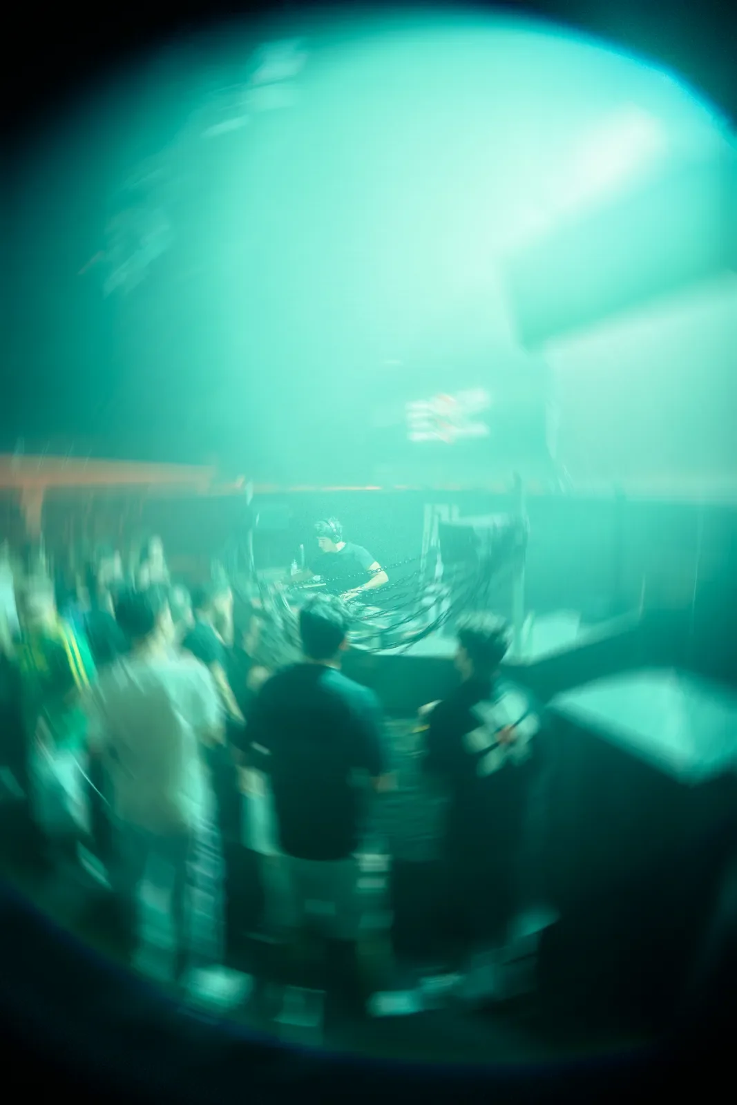 Escenario con personas desde un ángulo de vista con enfoque borroso y efecto de luz azul, probablemente en un evento o concierto.