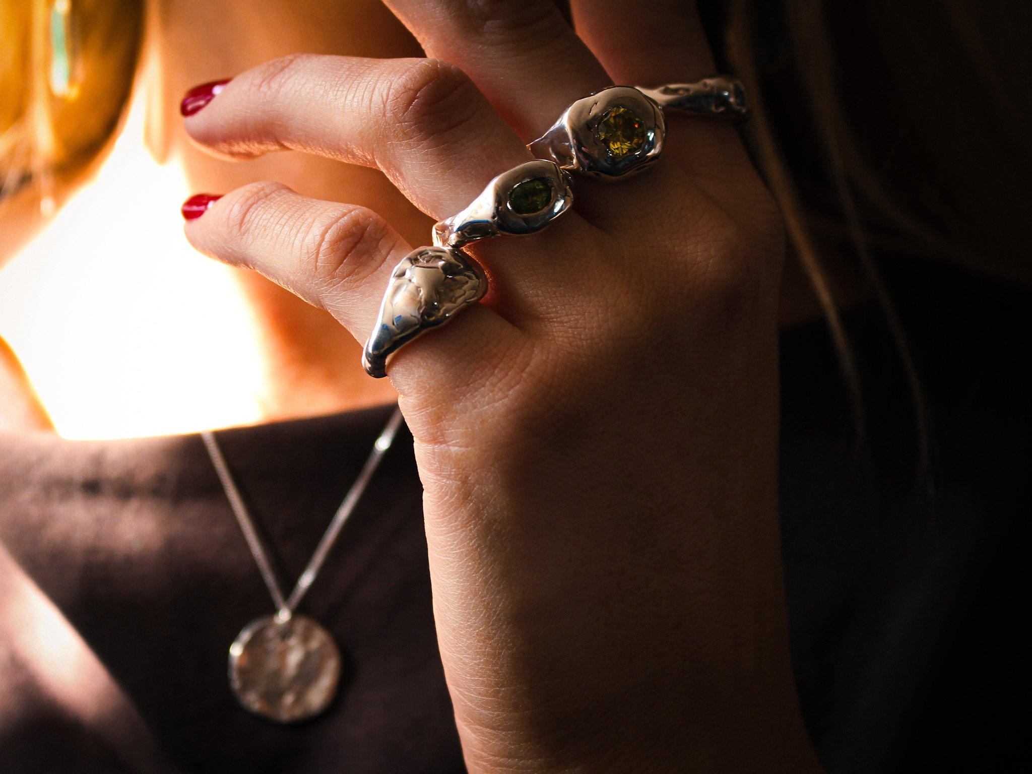 Close-up of a hand with silver rings and a necklace.