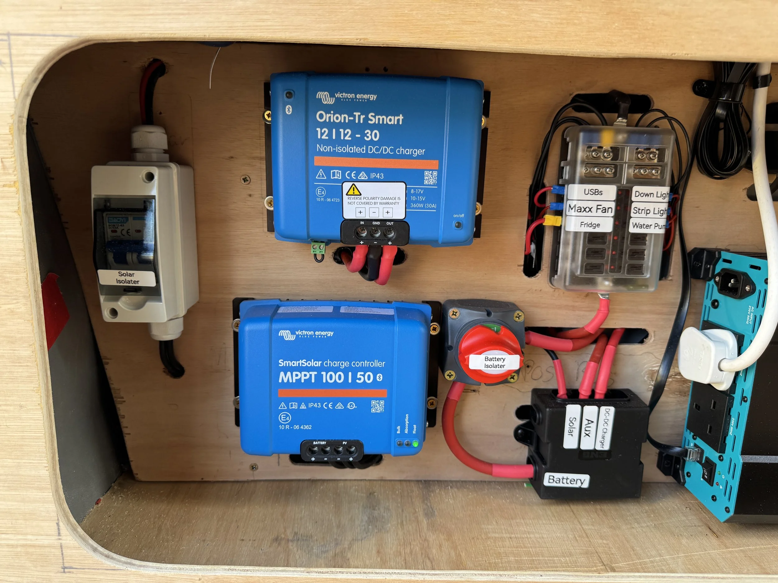 Interior of a solar power system with blue chargers, a solar isolator, and various electrical components.