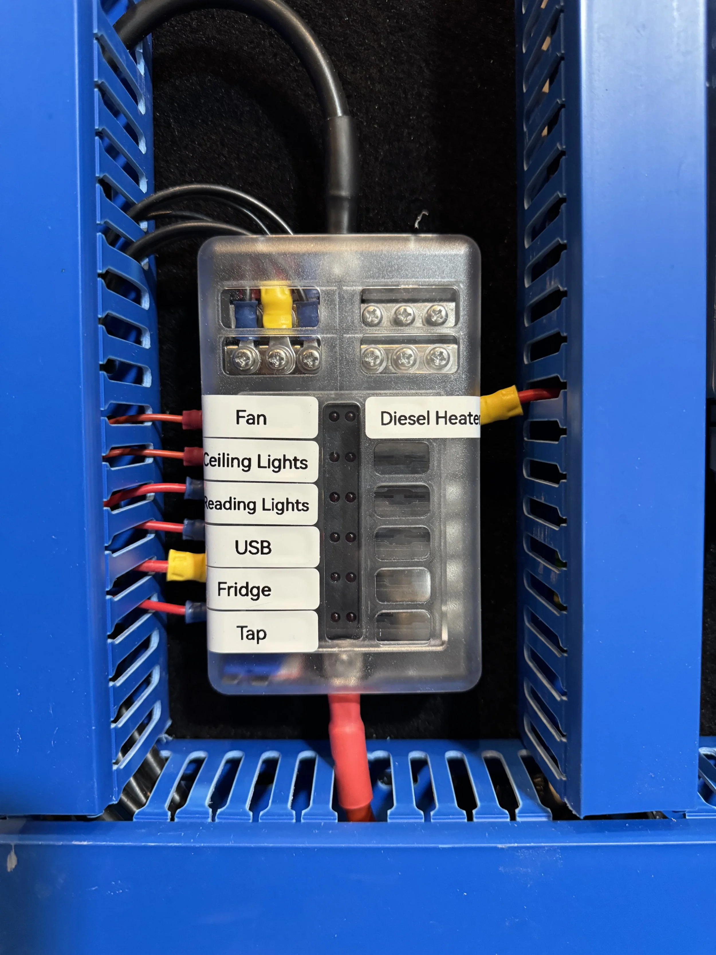 Electrical control panel with labeled switches for fan, ceiling lights, reading lights, USB, fridge, tap, diesel heater, and additional wires.