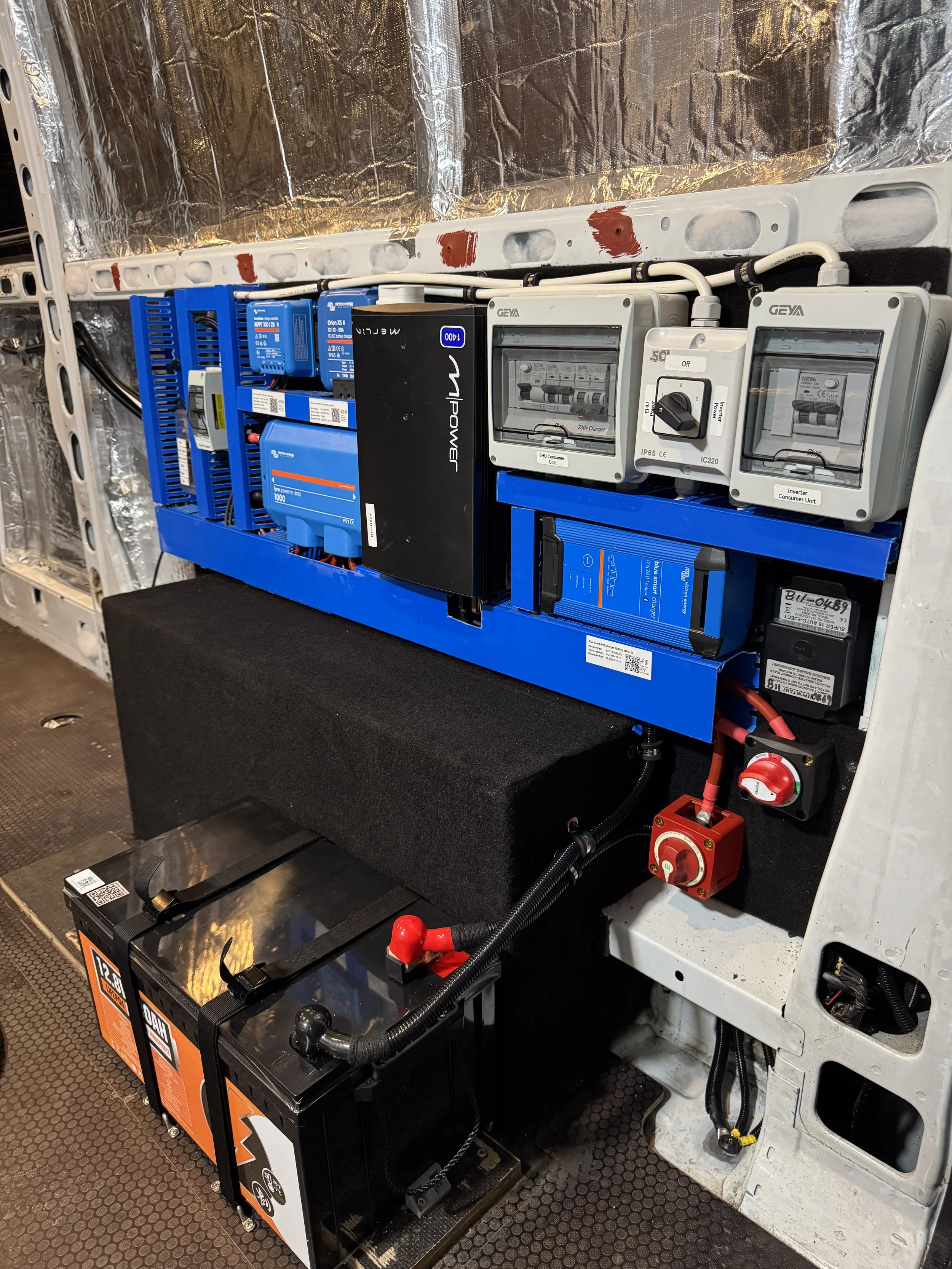 Electrical control panel with various switches, circuit breakers, and batteries installed inside an industrial or electric vehicle.
