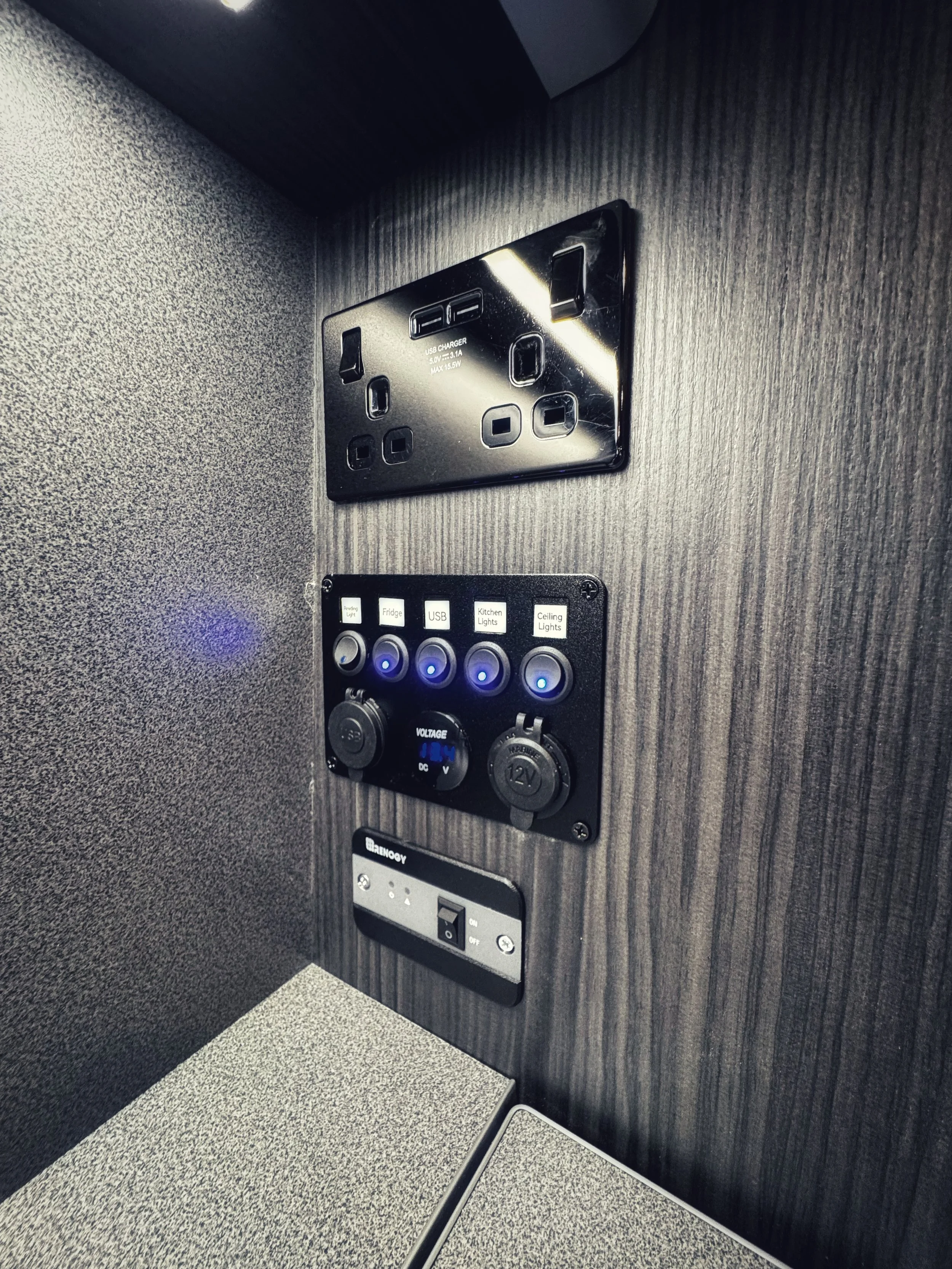 Control panel with switches and outlets, including USB chargers, power sockets, and voltage indicators, mounted on a wood-grain surface.