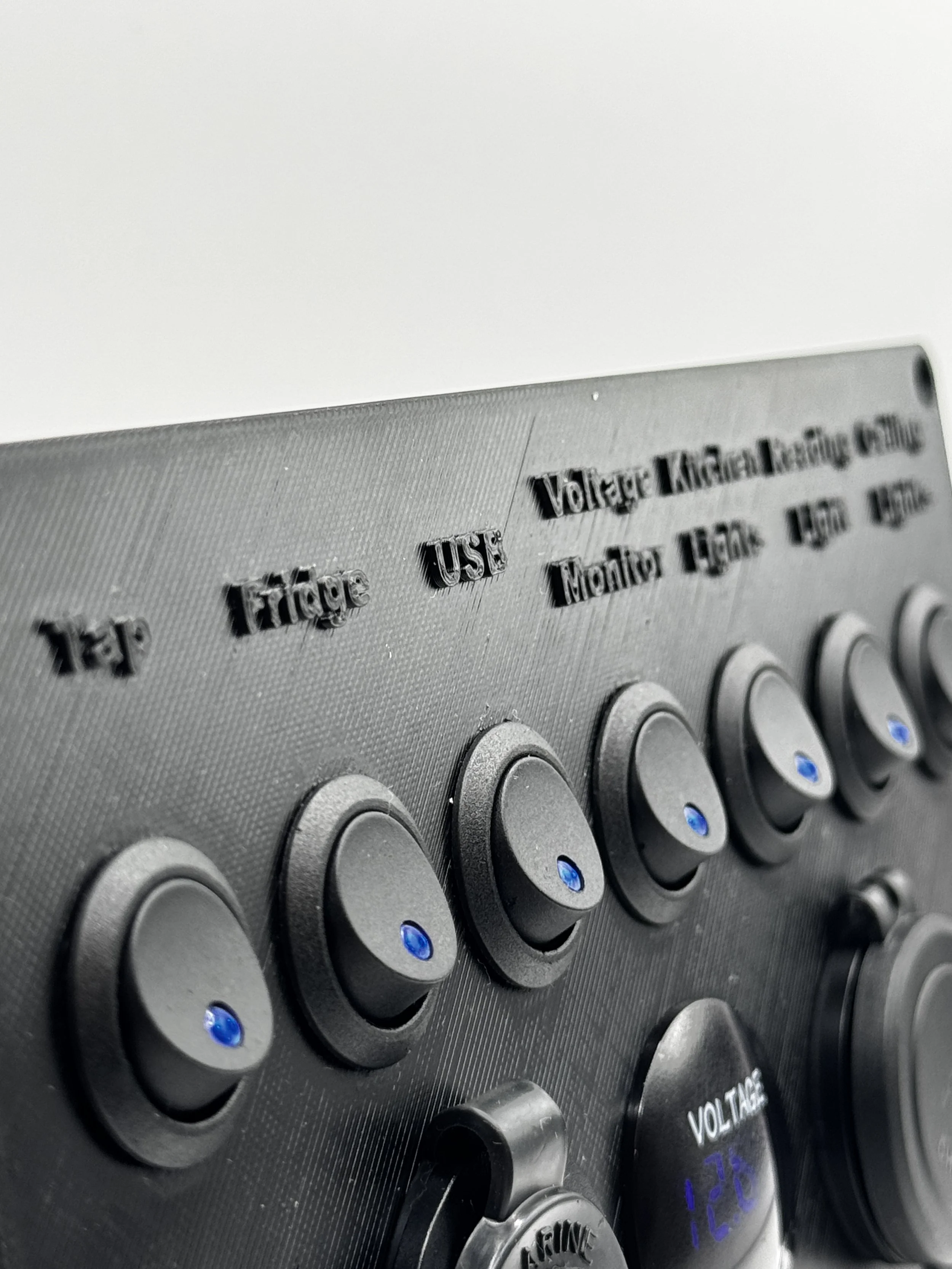 Close-up of a control panel with knobs and labels for electricity settings, showing voltage, fuse, and meter buttons.