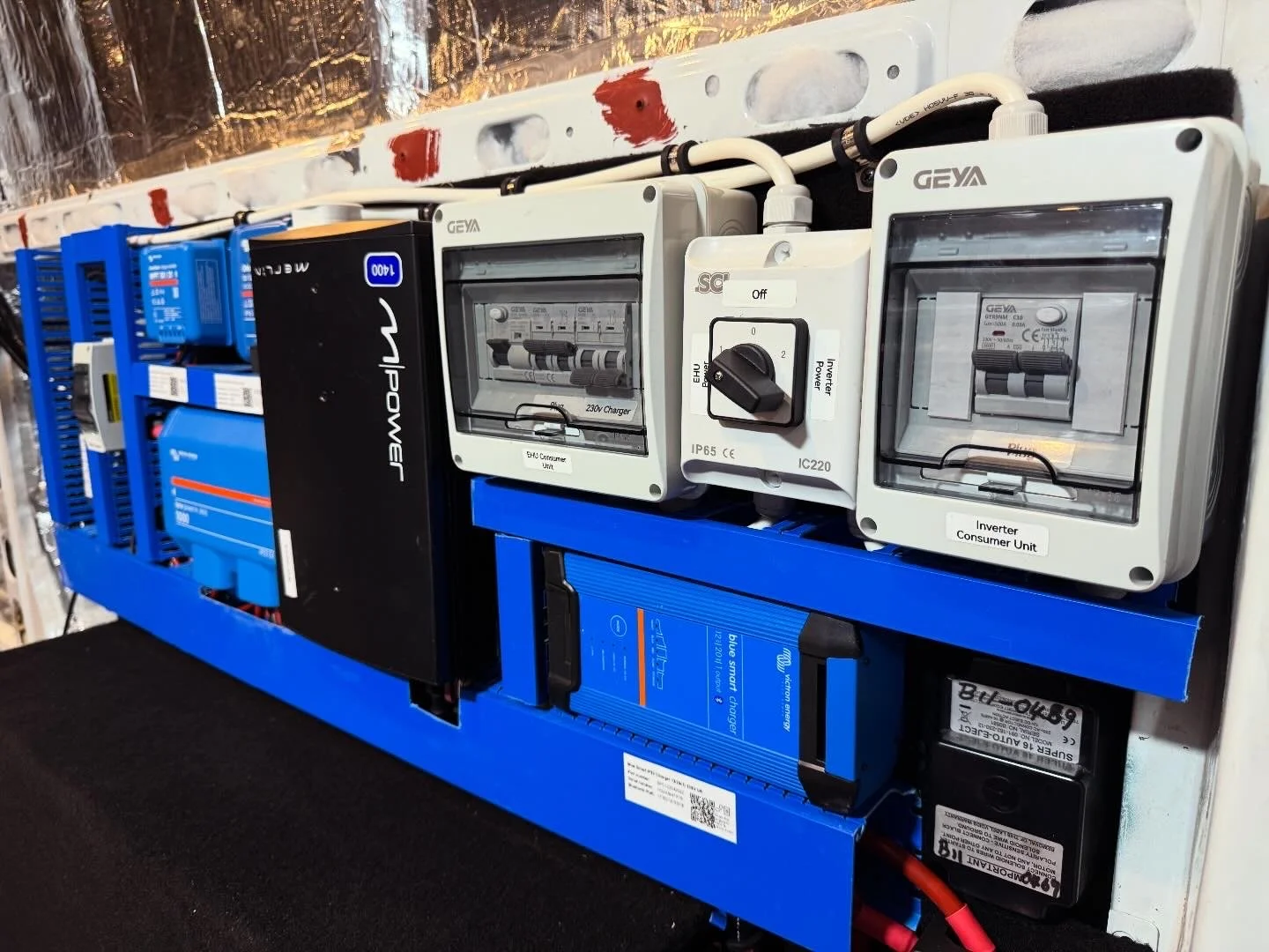 Electrical control panel with various circuit breakers, switches, and inverters in a blue metal frame.