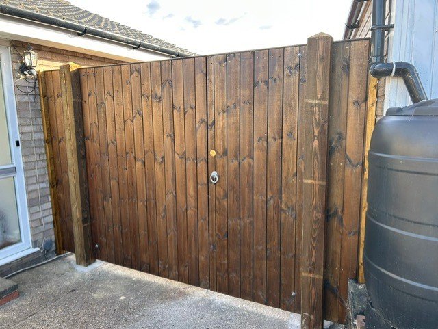 Wooden backyard fence with a small padlock and a reflective yellow sticker.