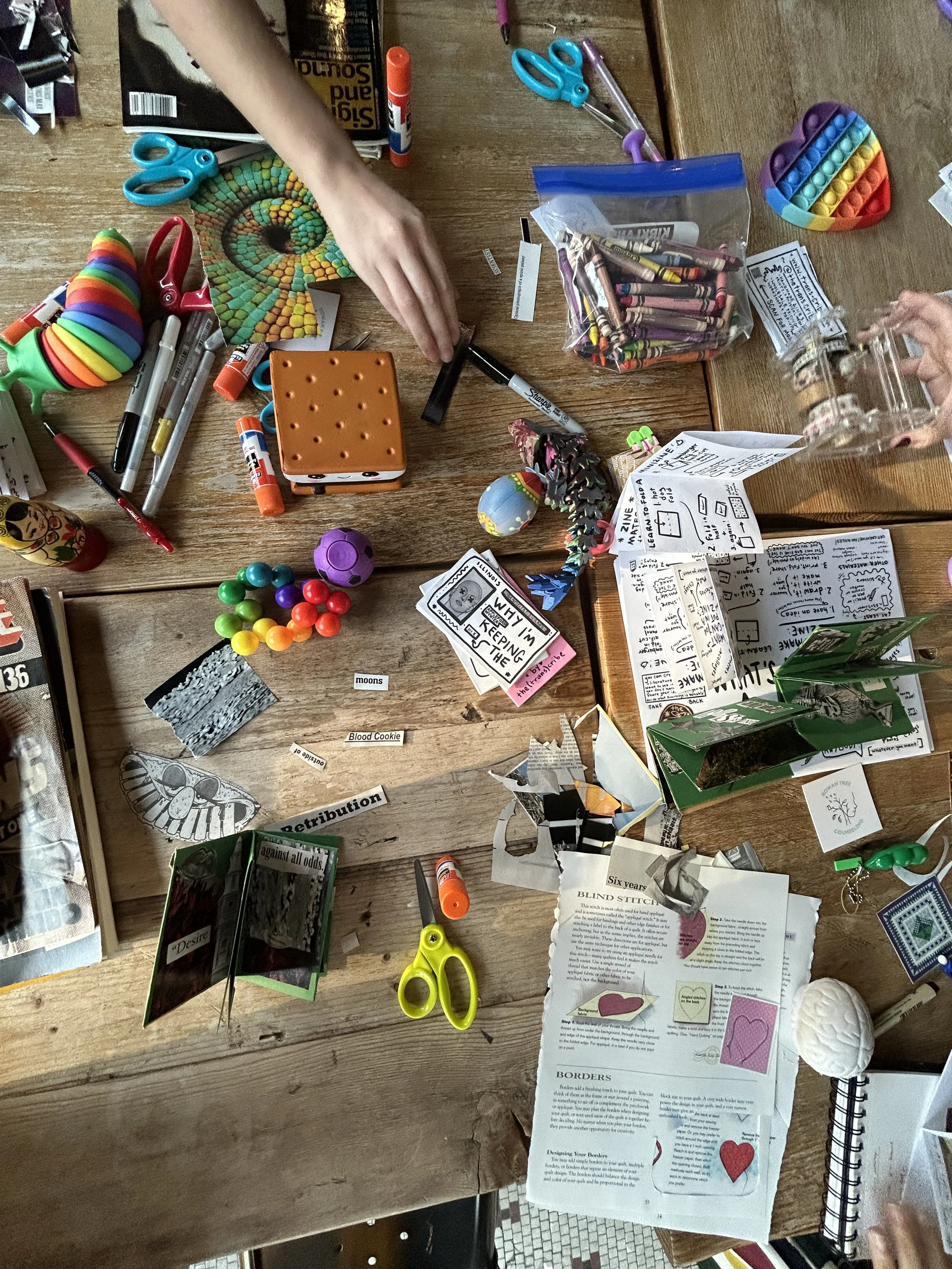 An above "craftermath" shot of a neurodivergent-friendly zine-making workshop mid-collage. 