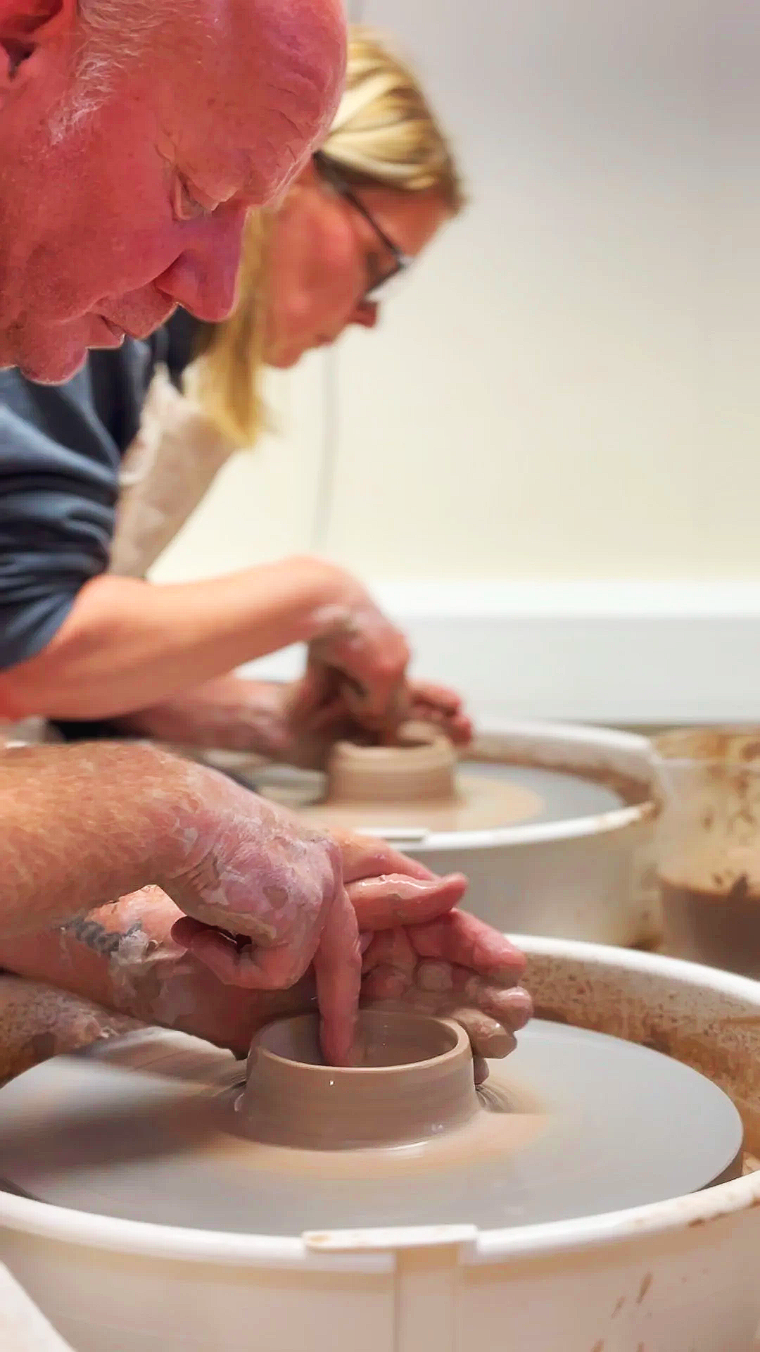 clay pot thrown on potters wheel with hands guiding it