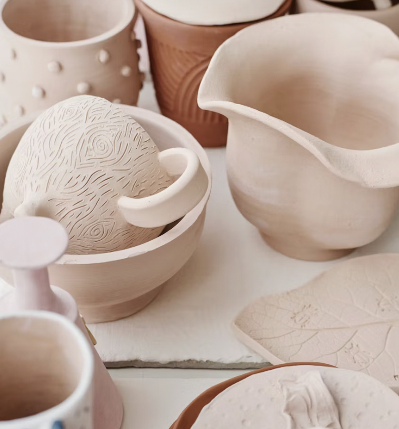 a person holding a brown ceramic mug in two hands wearing a cardigan