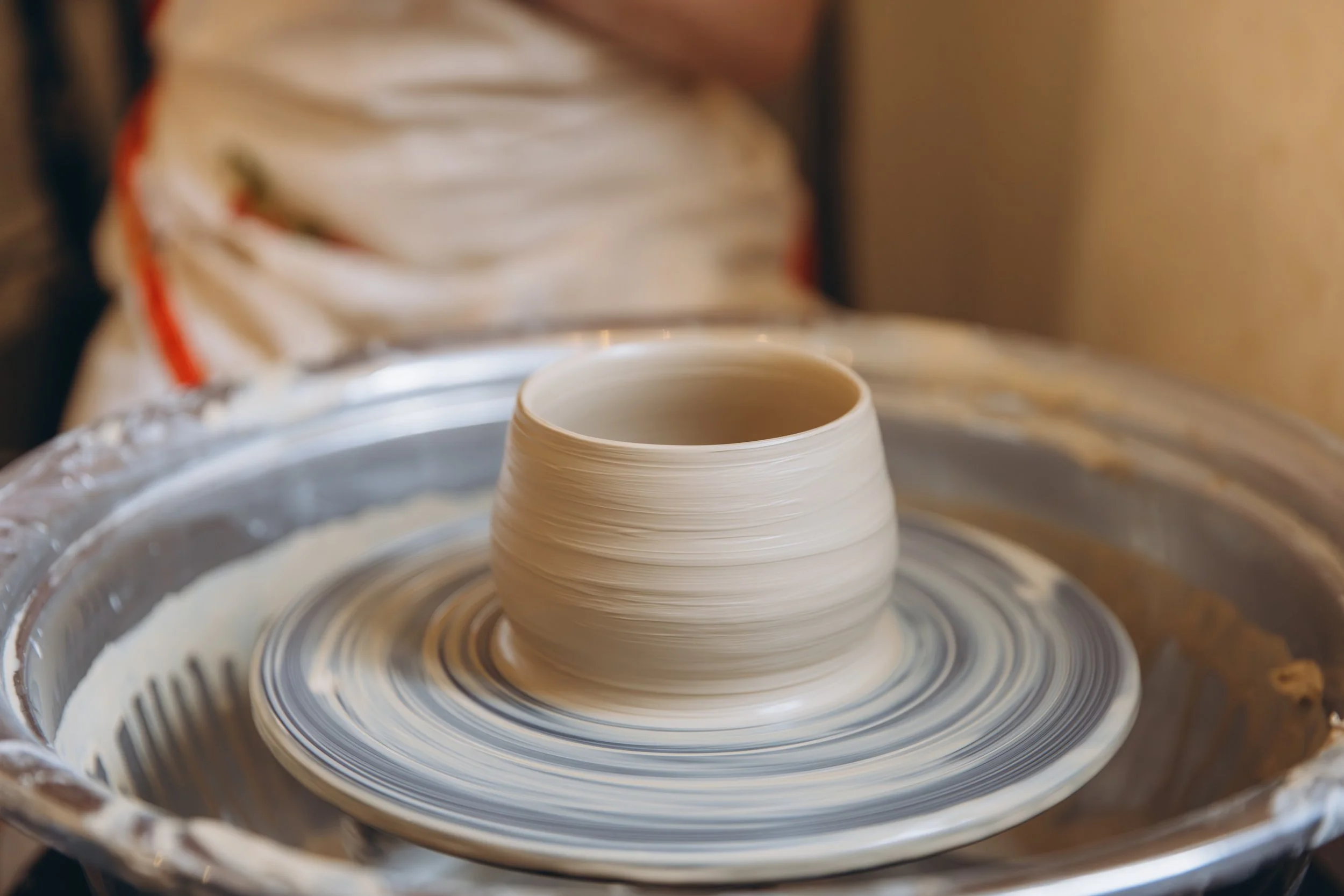 ceramic plate thrown on a potters wheel with hands cradling it