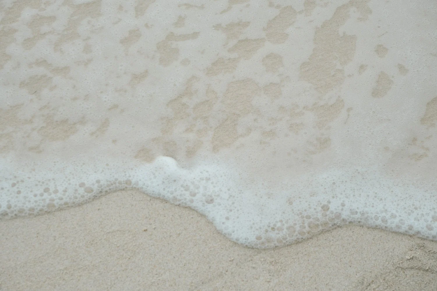 Ocean waves washing gently over dark sand, symbolising movement, discernment, and reflection.