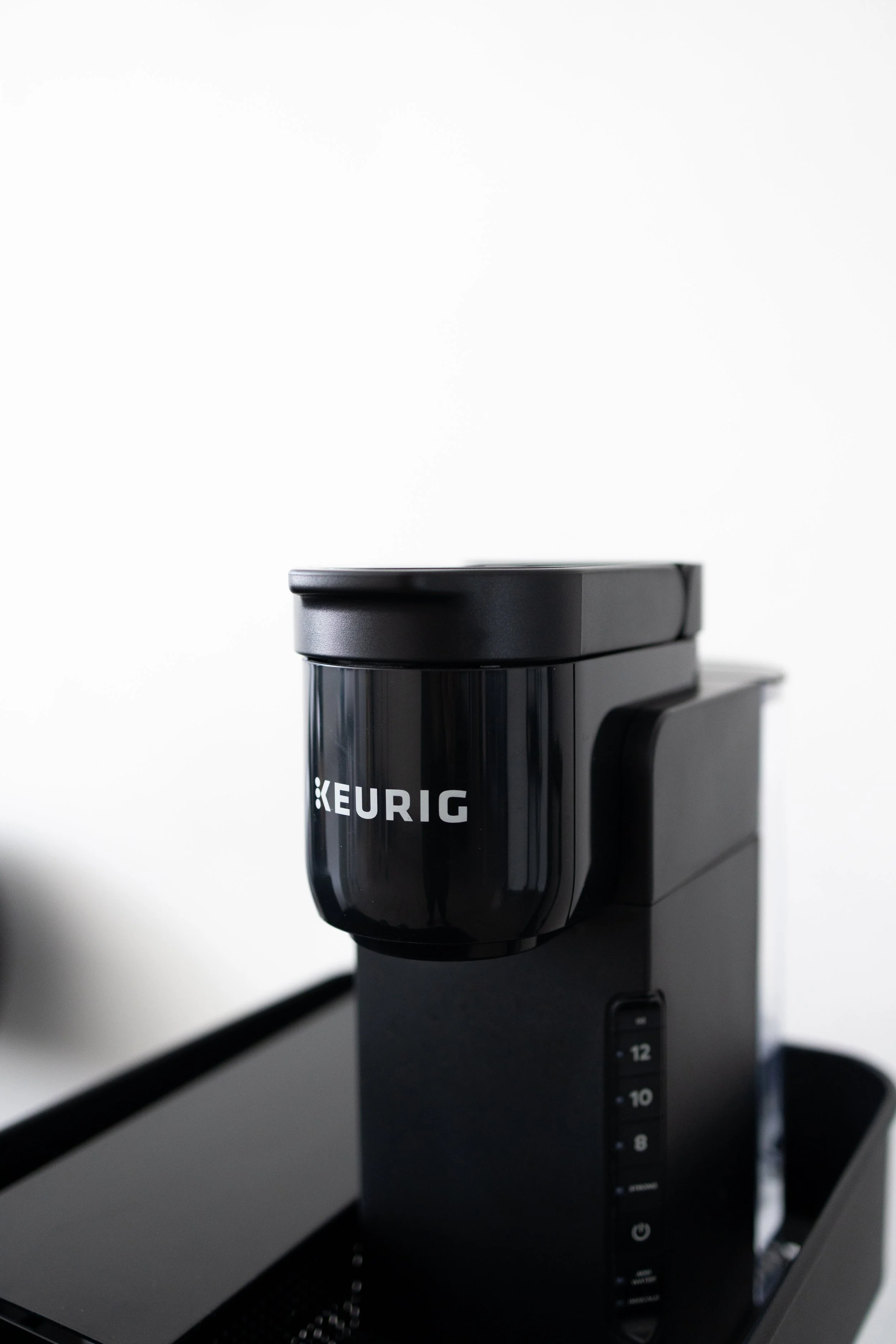 Black Keurig coffee machine on a black surface against a white background.