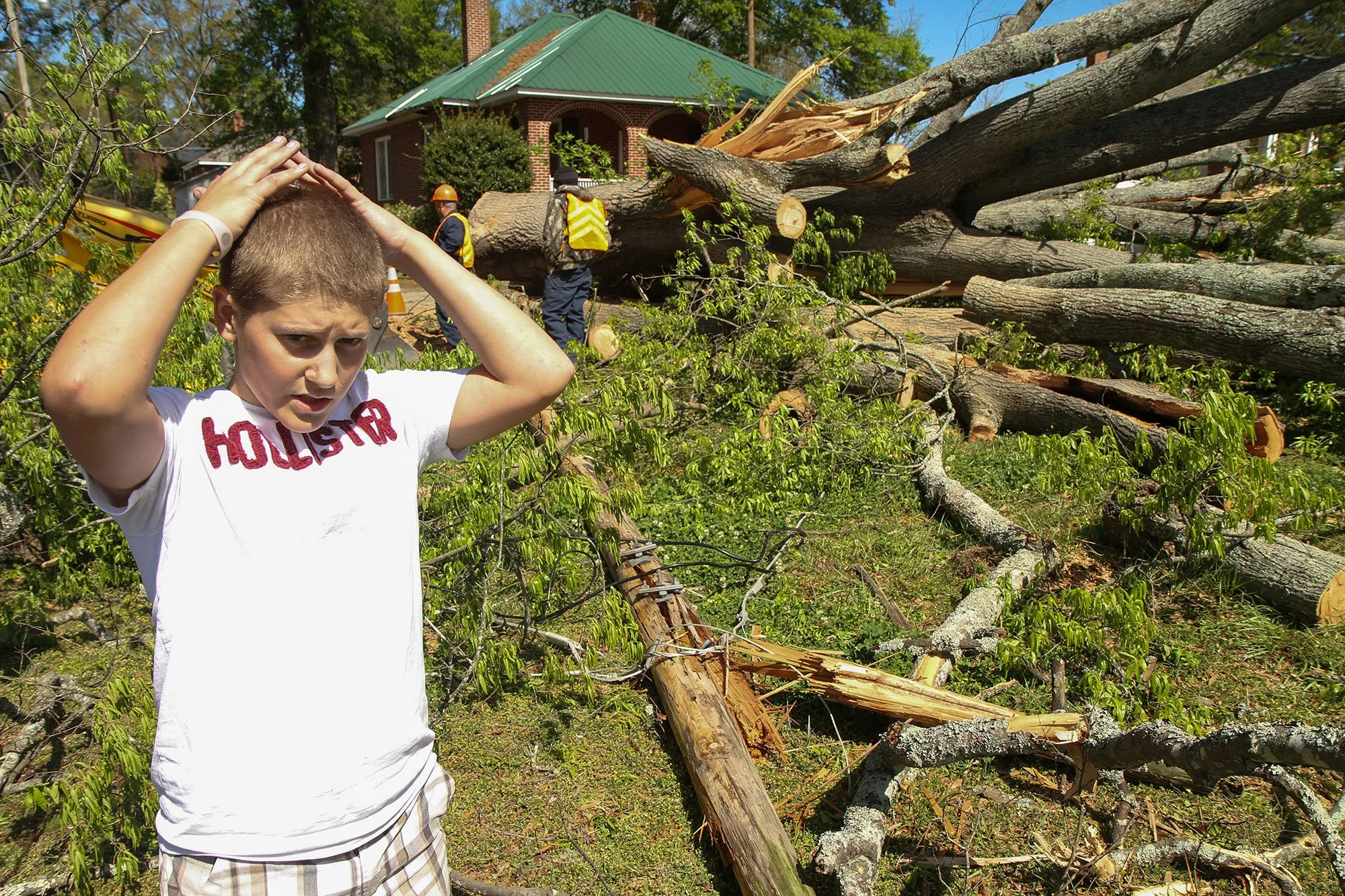 Dalton Mars, 14, stands in his yard at 307 Dukes Ave. on Tuesday morning as a Greerwood CPW crew removes a tree that fell onto his father's two-month-old truck and through his home's ceiling. The family was not injured when
the tree fell at 1:30 a.m.