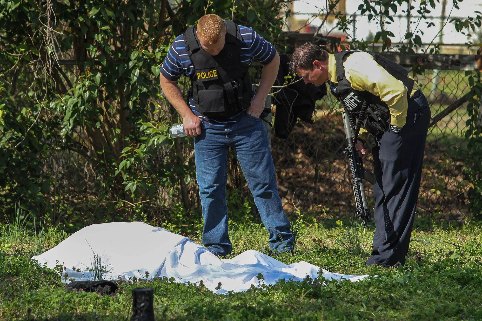 Law enforcement officials examine the body of Daniel Phillip Chapman Jr., who was killed on Reynolds Avenue on March 16, 2011. Members of the Greenwood Drug Enforcement Unit were assisting in Chapman’s apprehension when he fled a residence on Jordan 