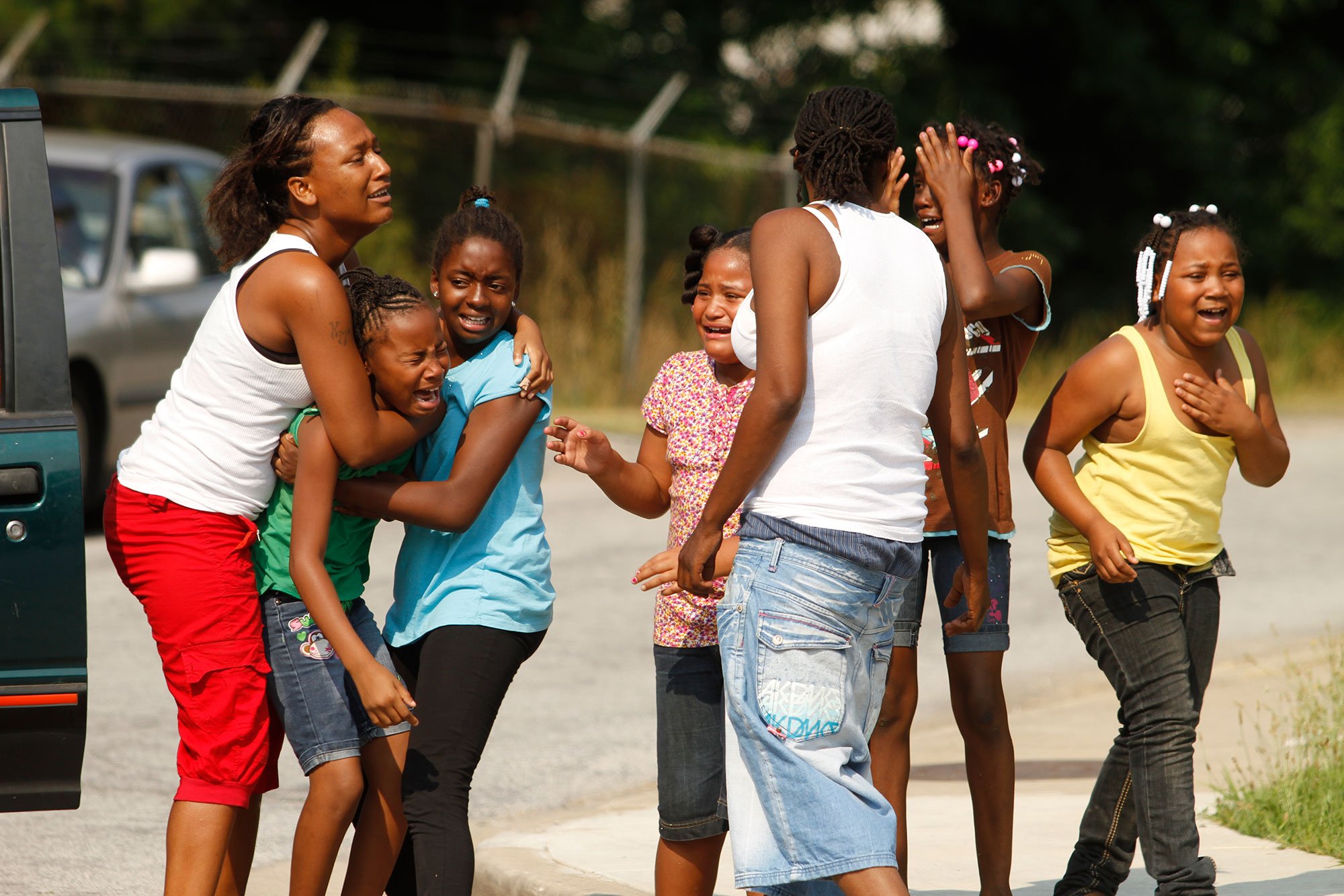 Keisha Martin, far left, cousin of the 7-year-old girl struck by an SUV, holds back a girl in a group of children emotionally shaken by the bicycle wreck on Taggart Avenue on June 9, 2011. The girl was riding west on Taggart Avenue and crossing New M