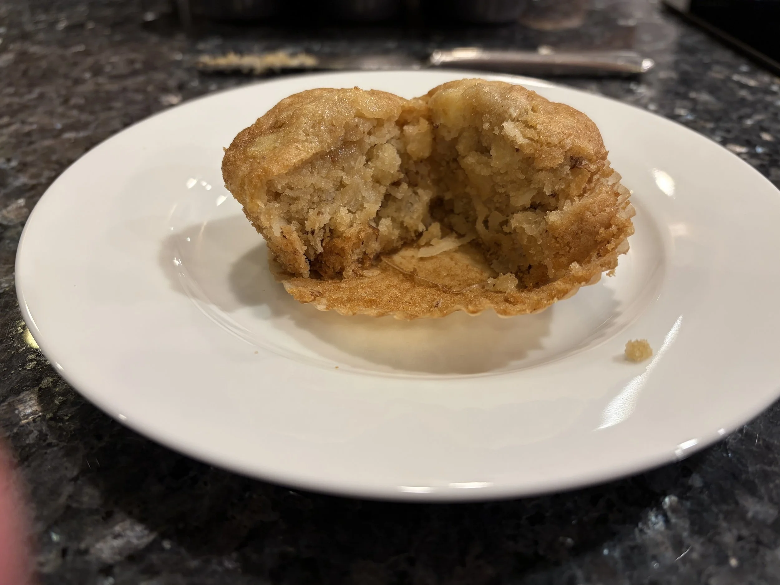 Gluten-free apple walnut muffin cut open to show its moist texture and apple pieces.