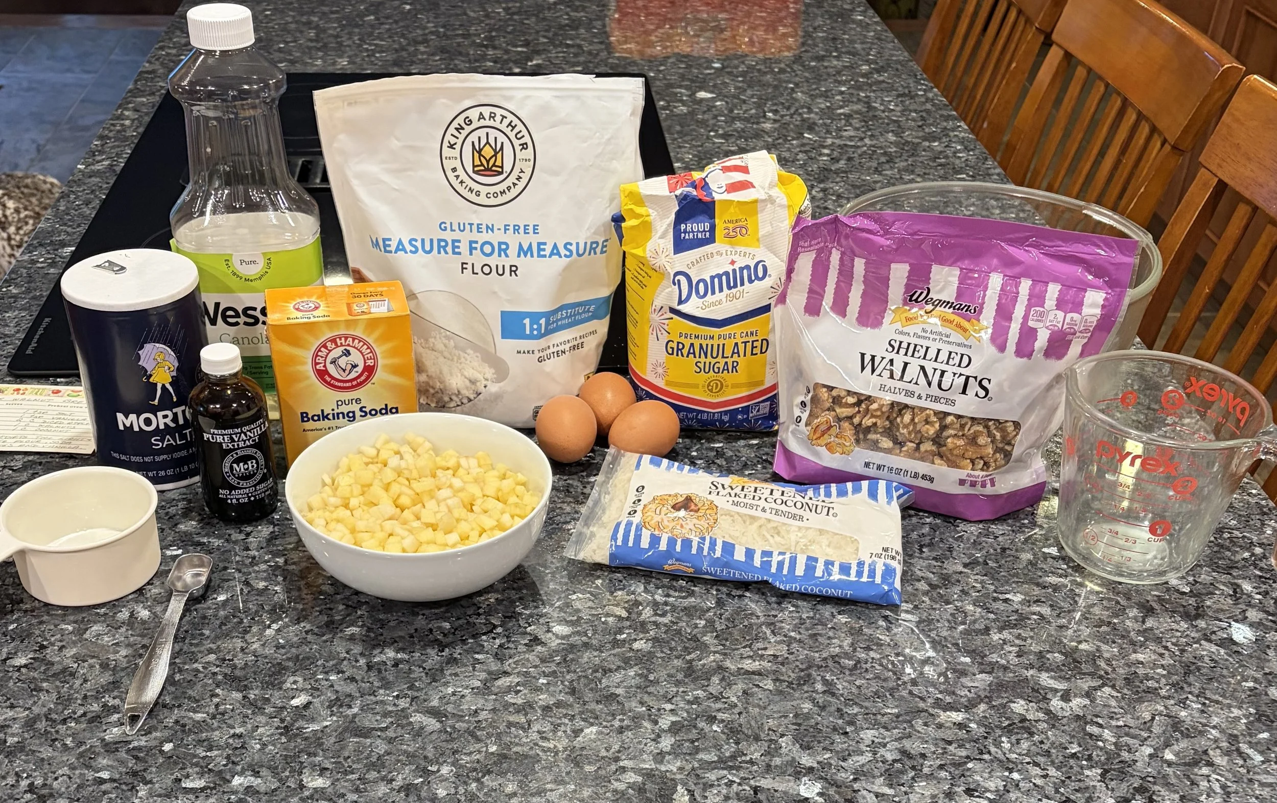 Ingredients for gluten-free apple walnut muffins, including apples, walnuts, flour, eggs, and sweetened coconut.